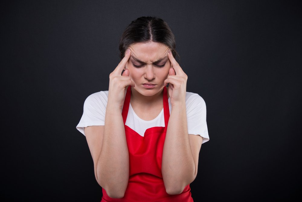 Distressed restaurant worker with red apron | Photo: Shutterstock