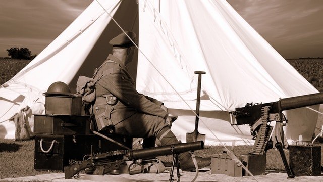 Un militar sentado y rodeado de armas. | Foto: Pexels/Mike