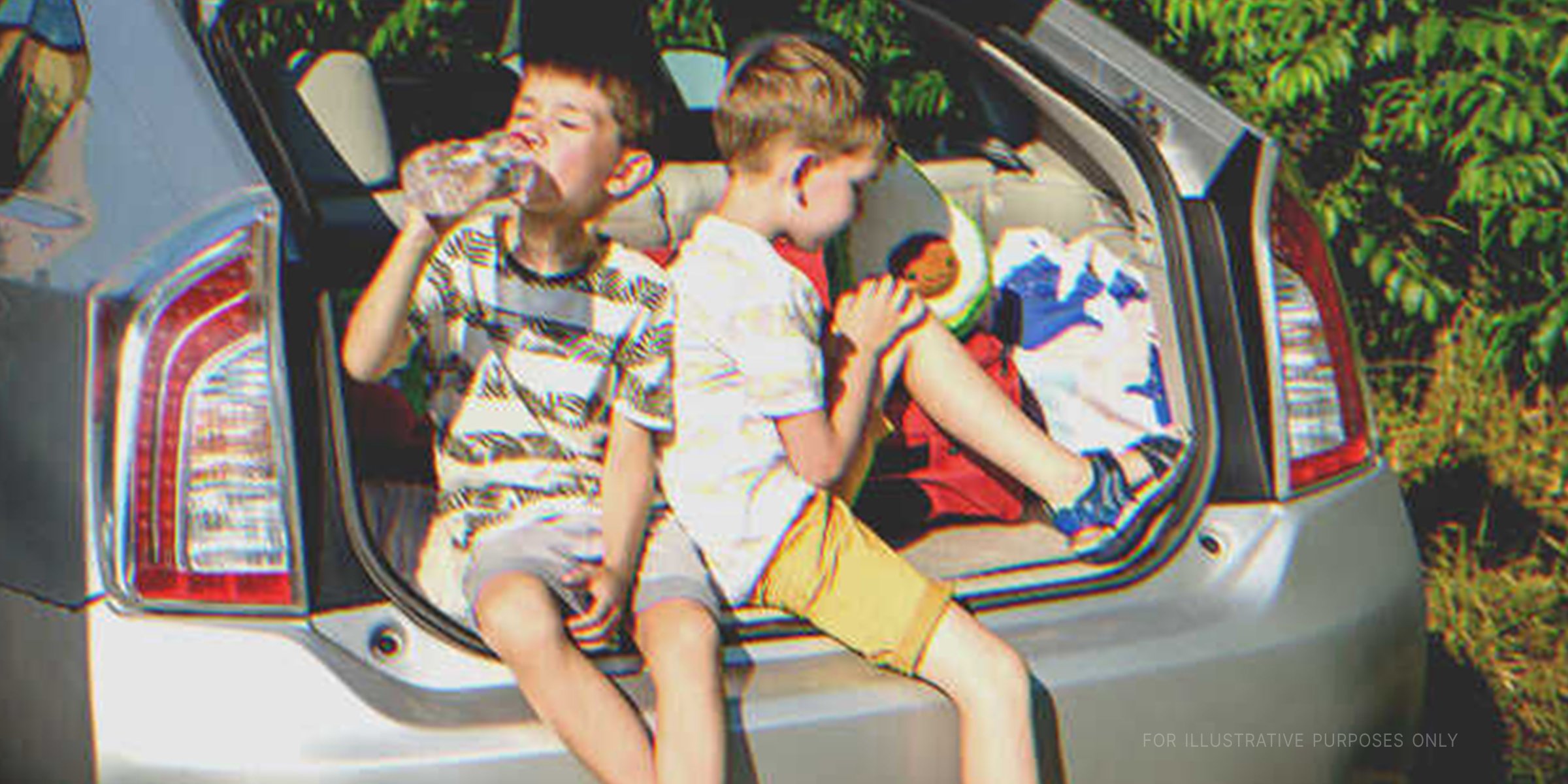 Two boys sitting in a car trunk | Source: Shutterstock