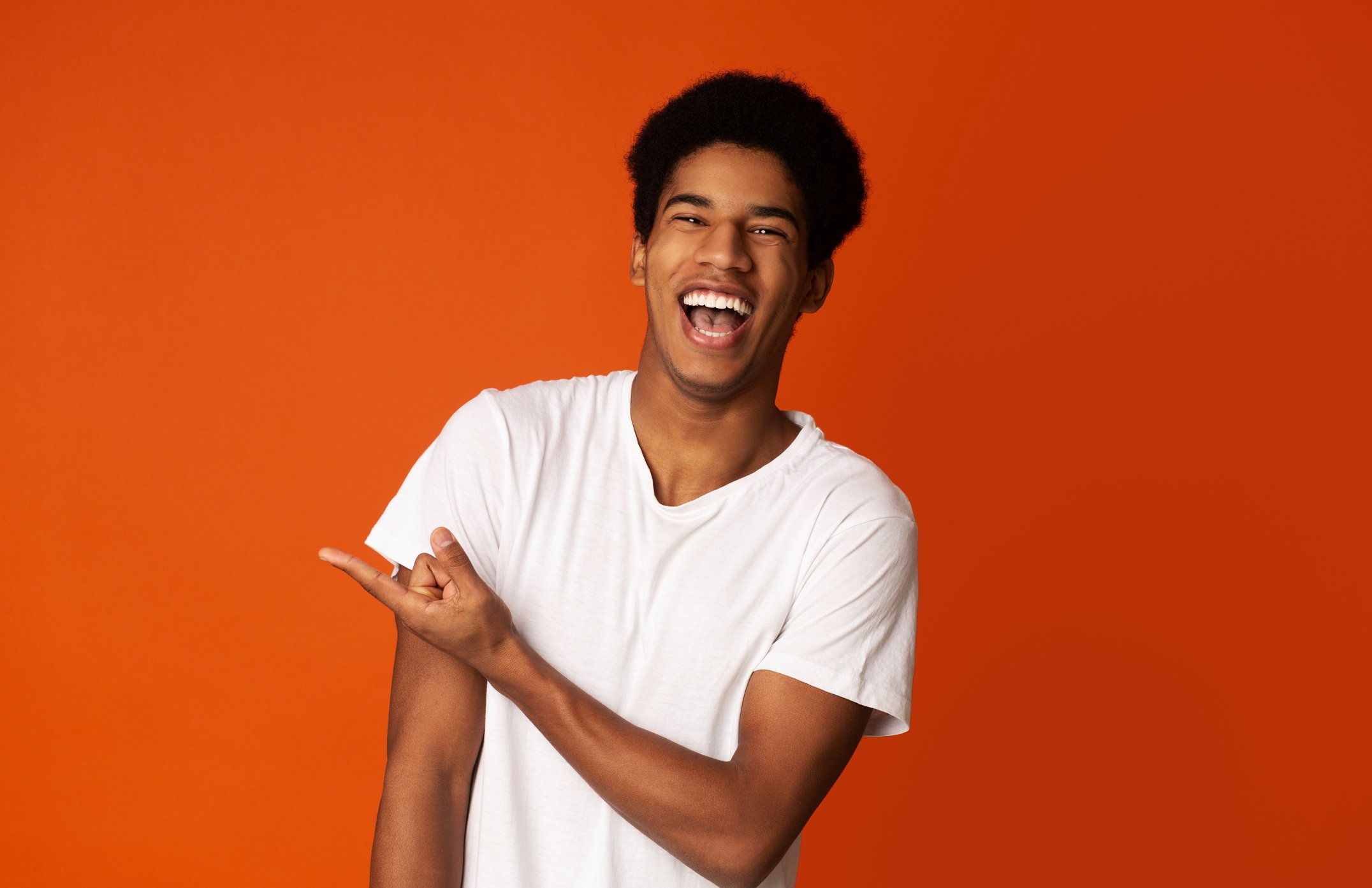 A man in a white shirt laughing while pointing a finger. | Photo: Getty Images