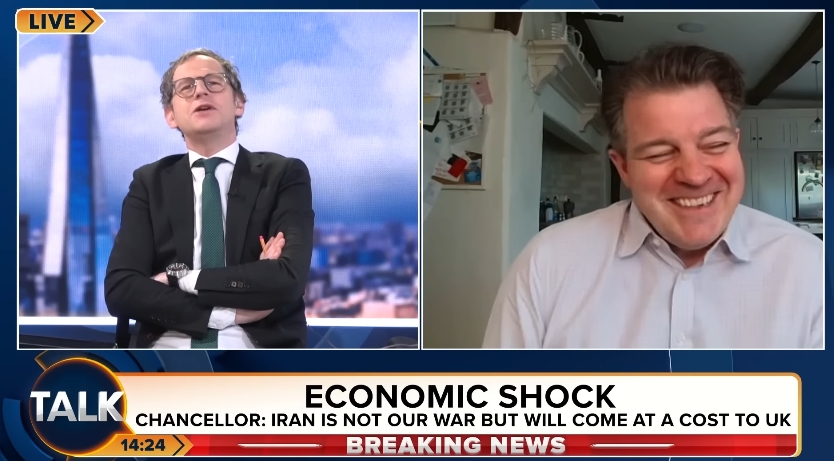 Appearing from a home setting, Liam Halligan balanced serious economic commentary with a noticeably warm and easygoing presence, briefly smiling as the conversation shifted from IMF forecasts to headlines surrounding his growing closeness with Kate Garraway. | Source: YouTube/TalkTV