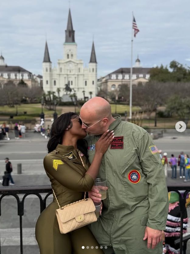 , Joe McCann and Ashly Robinson share a spontaneous kiss, their embrace blending romance with the lively energy of the city behind them. | Source: Instagram/ashleejenae
