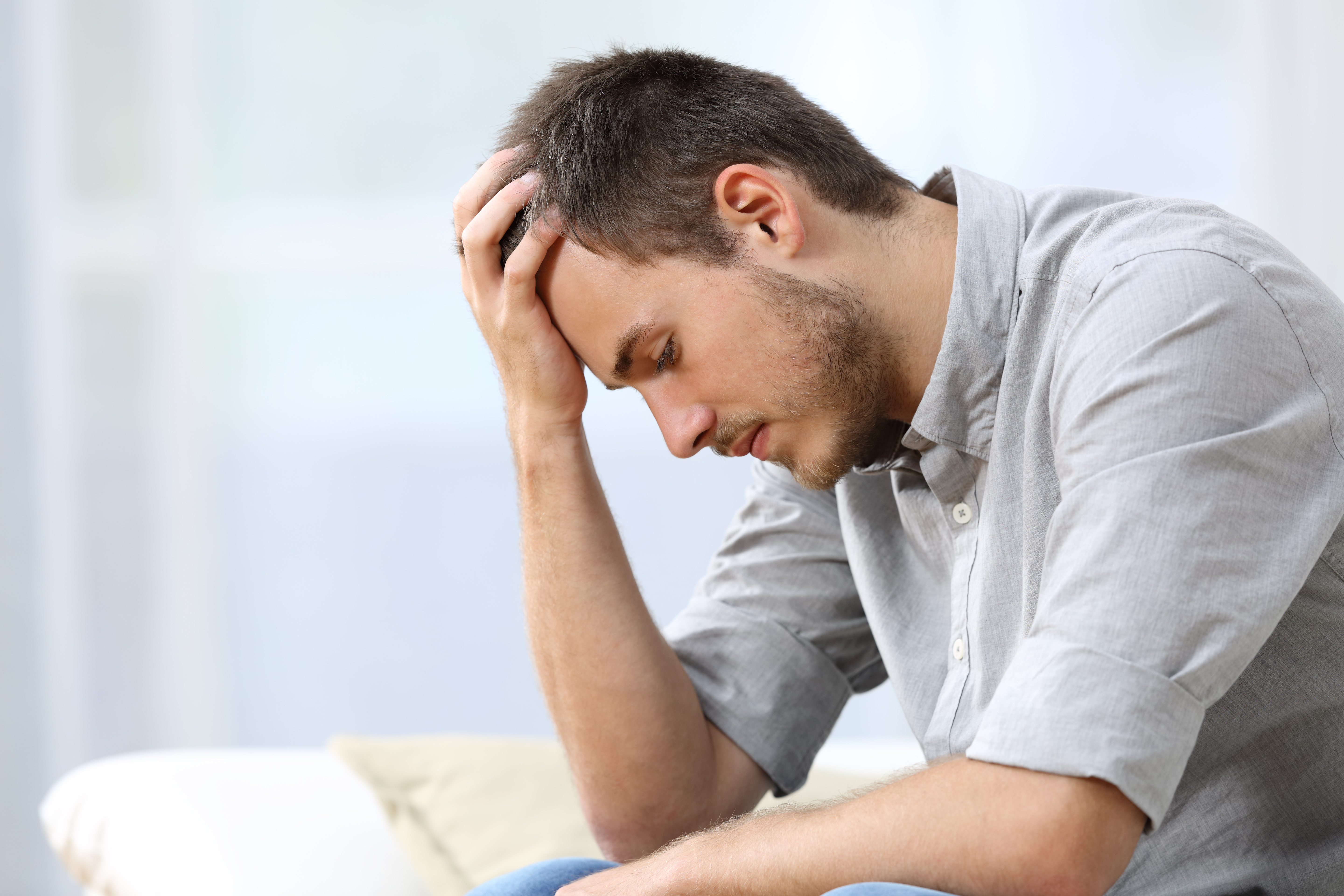 A man with his head bowed down in worry | Source: Shutterstock