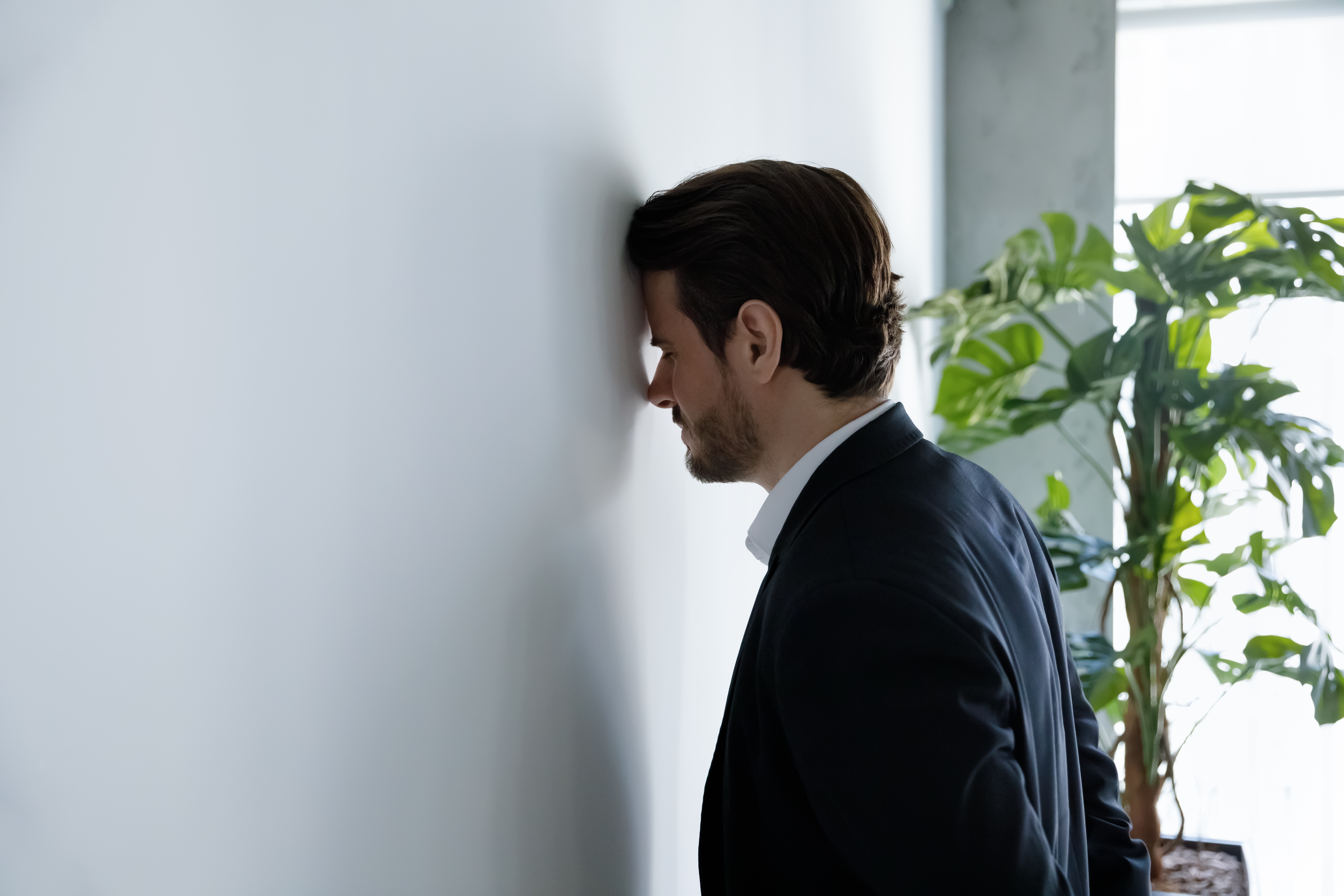 An upset businessman banging his head against a wall | Source: Shutterstock
