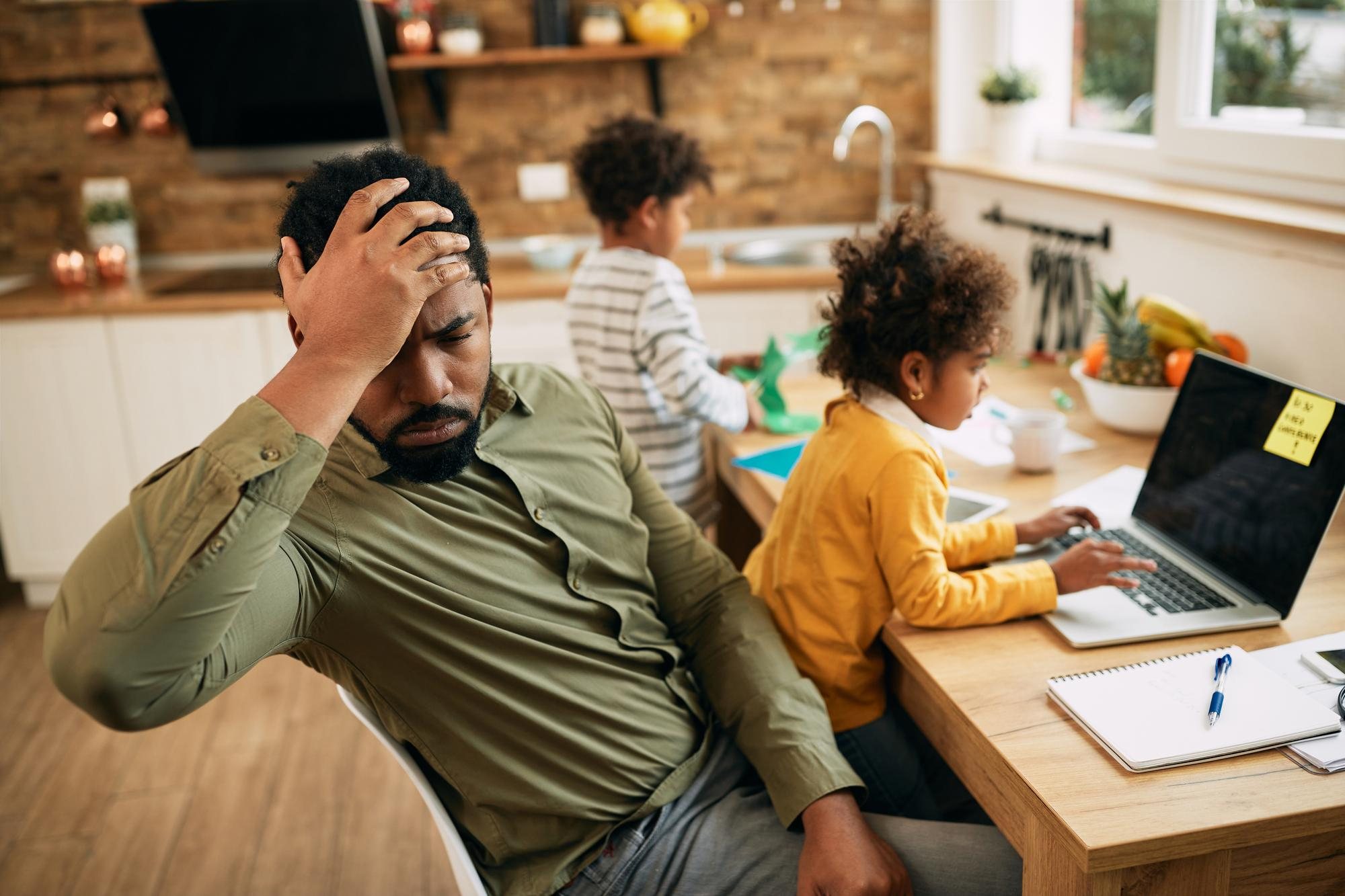 A stressed man sitting with his children | Source: Freepik