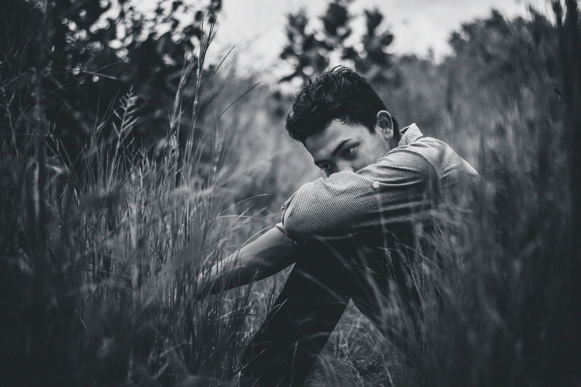 Un hombre con expresión triste, está sentado al aire libre. | Foto: Pexels