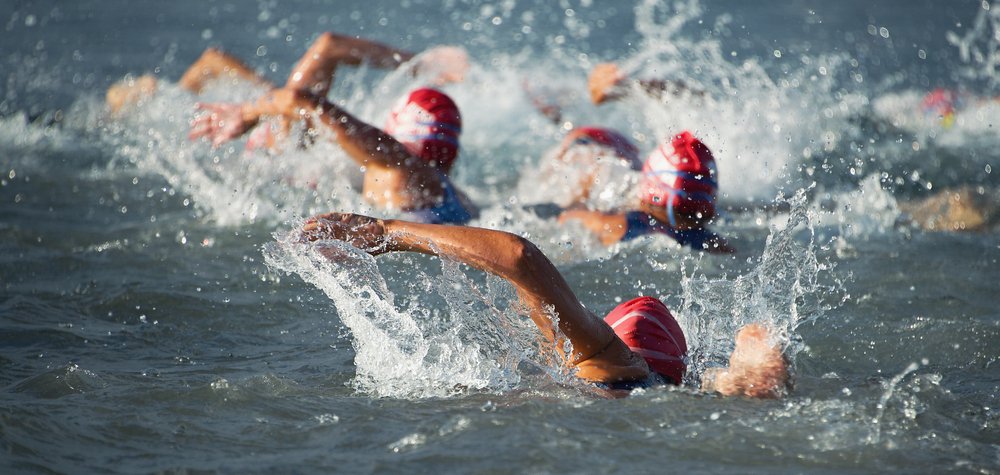 Wettbewerber, die zu Beginn des Triathlon ins offene Wasser schwimmen. I Quelle: Shutterstock