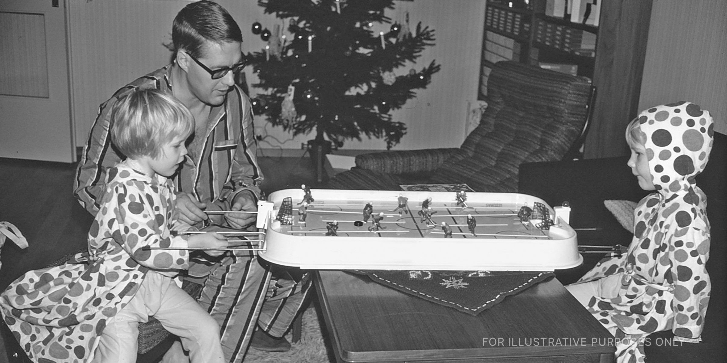 A father playing table hockey with his daughters. | Source: Getty Images