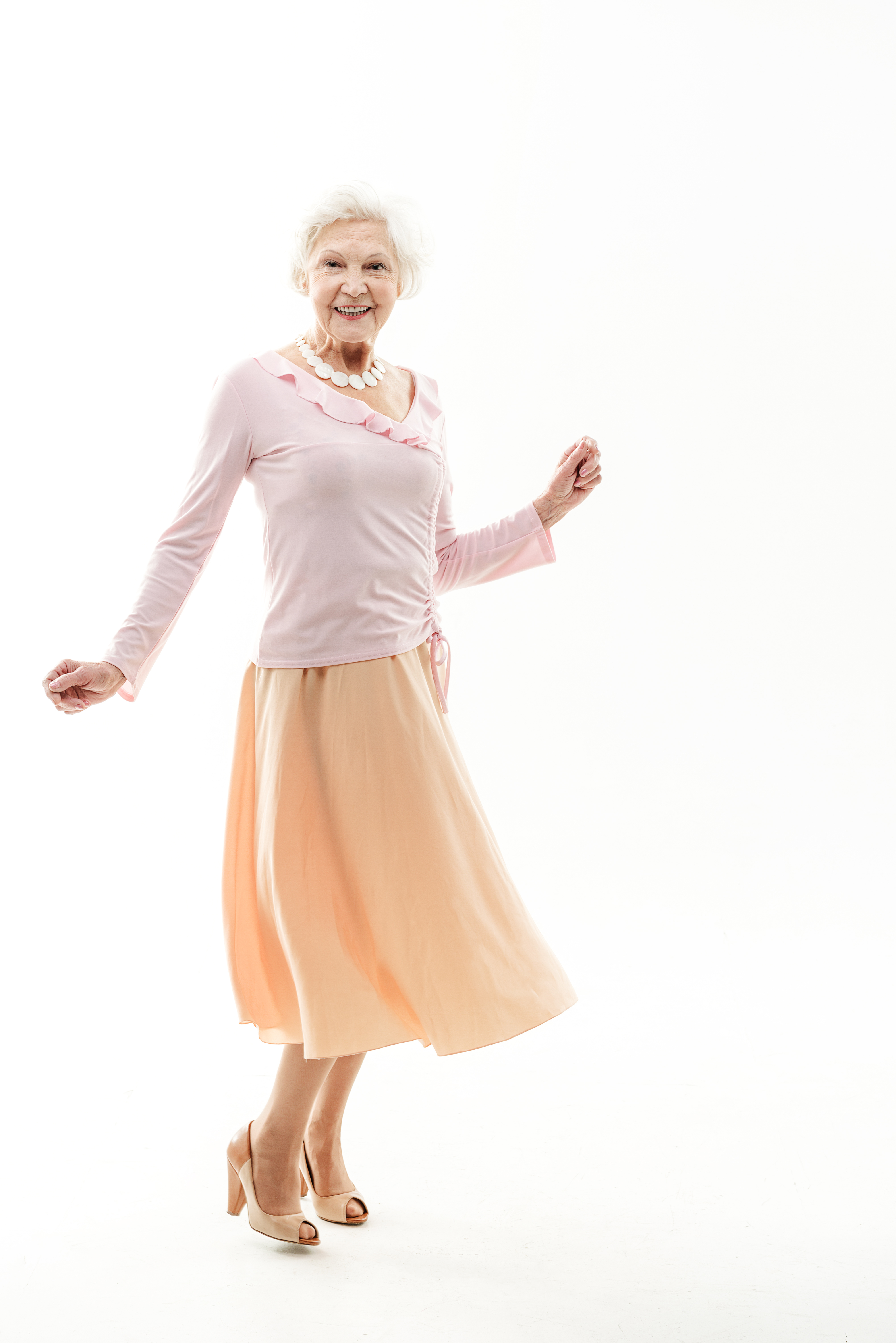 A carefree senior woman in a fitted top and flared skirt | Source: Shutterstock