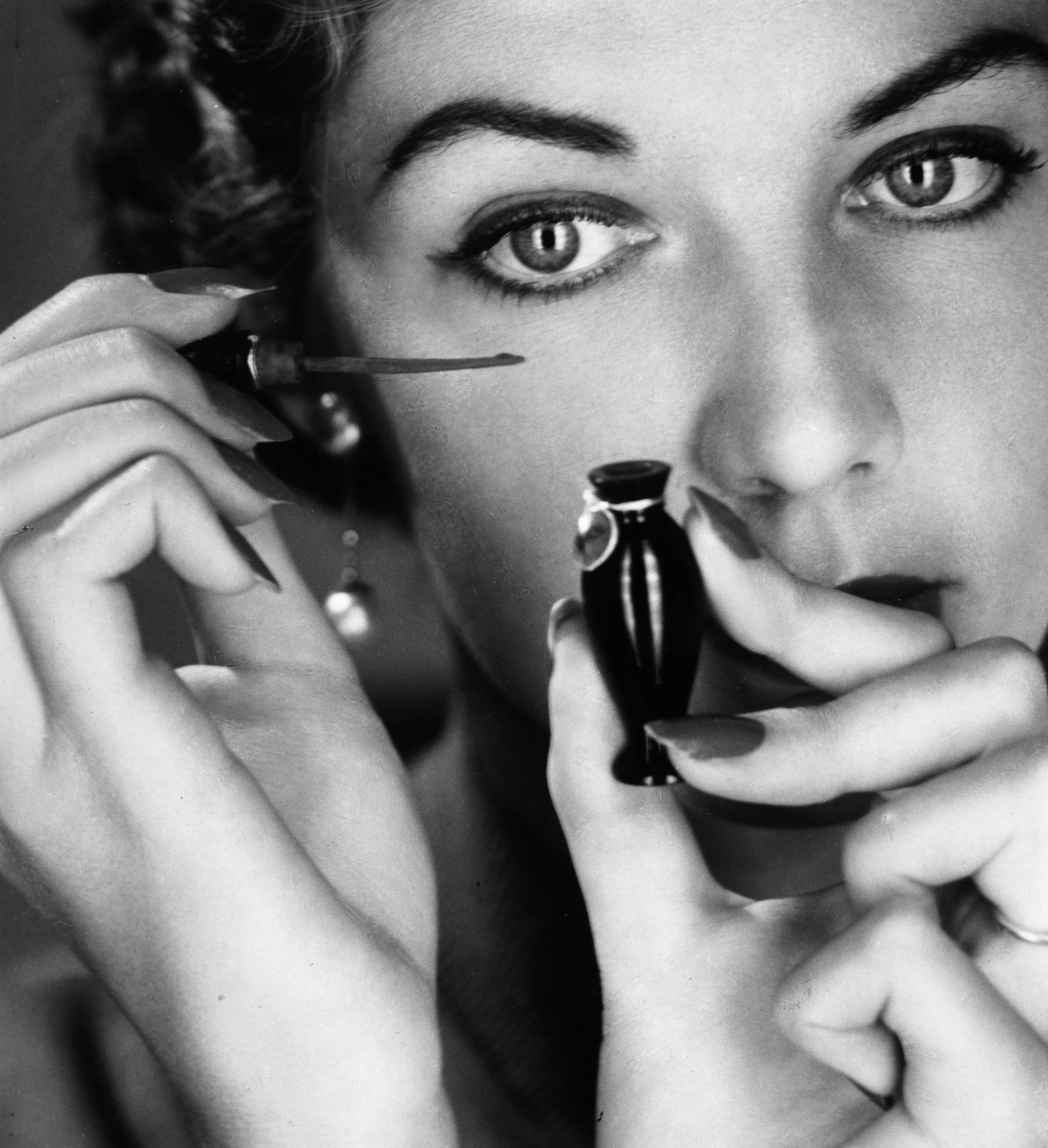 A woman applying eye makeup to her lids in 1955. | Source: Getty Images