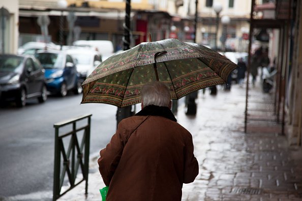Une vieille dame accroche un parapluie pour se protéger de la pluie. |Photo : Getty Images