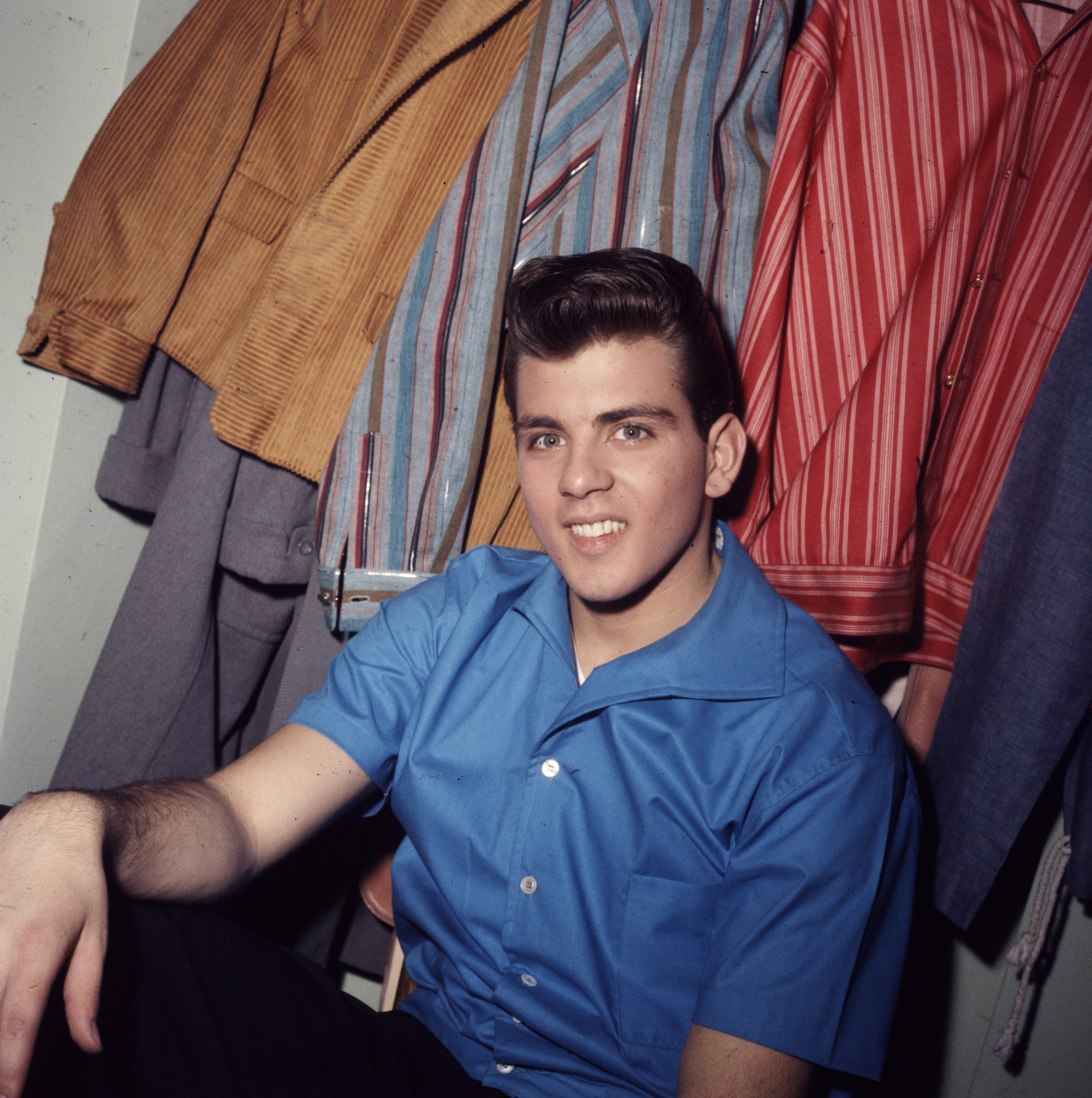 Portrait of American pop singer and actor Fabian smiling while sitting in front of several colorful striped shirts circa 1961. | Source: Getty Images
