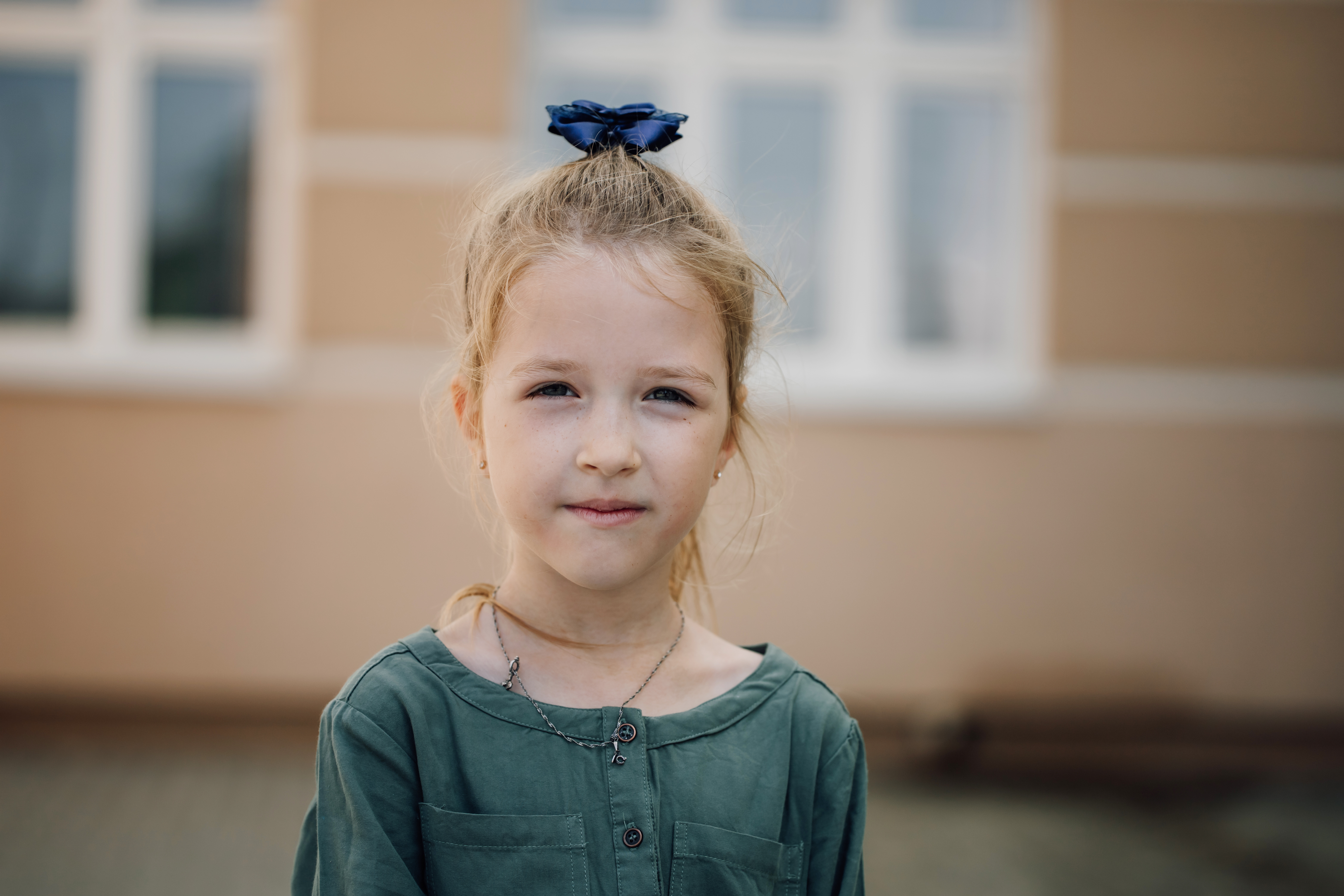Portrait of serious small girl looking at camera with elementary school building in background | Source: Getty Images