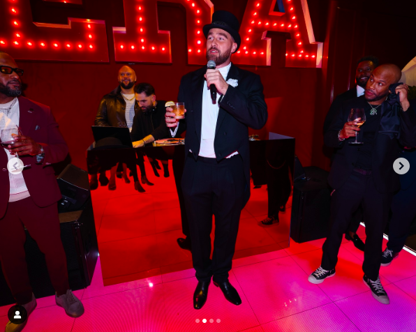 Travis Kelce speaking at the surprise party alongside guests, posted on December 19, 2024 | Source: Instagram/aricjones