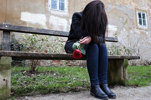 Sad woman holding a rose | Source: Pixabay