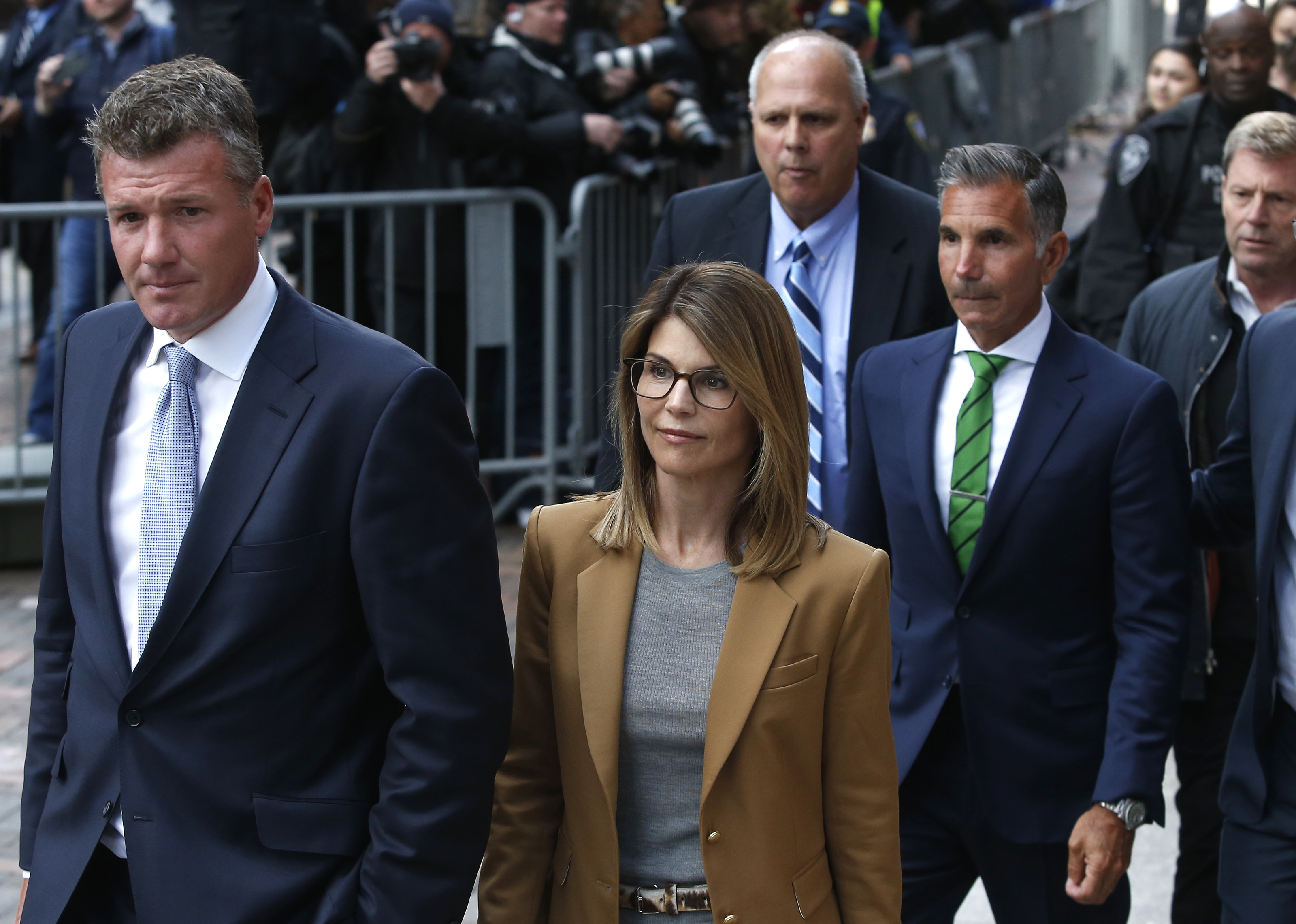 Lori Loughlin, in a tan coat, leaves Boston federal court with her husband Mossimo Giannulli, in a green tie, on April 3, 2019 | Source: Getty Images