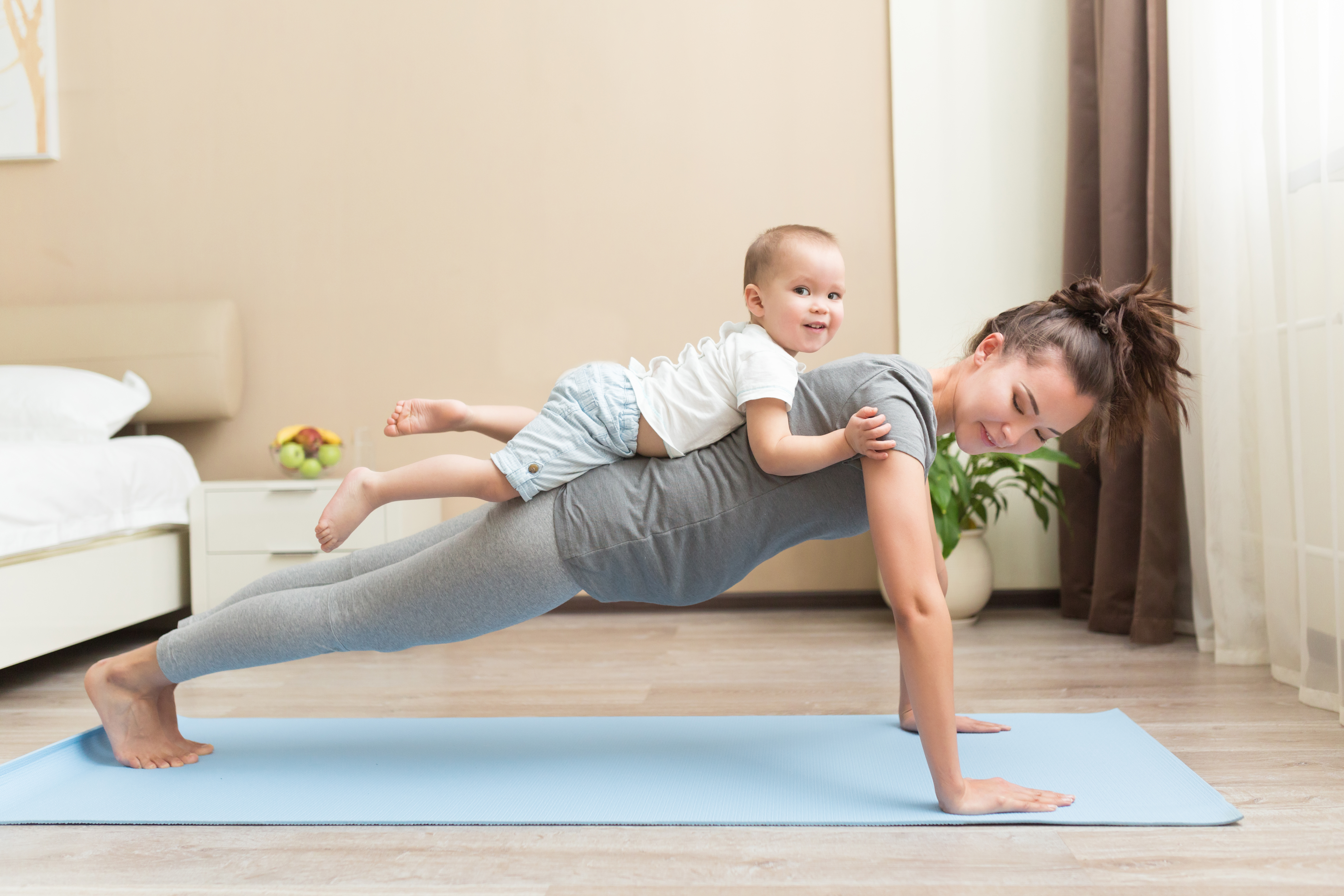 A woman exercising with her child on her back | Source: Shutterstock