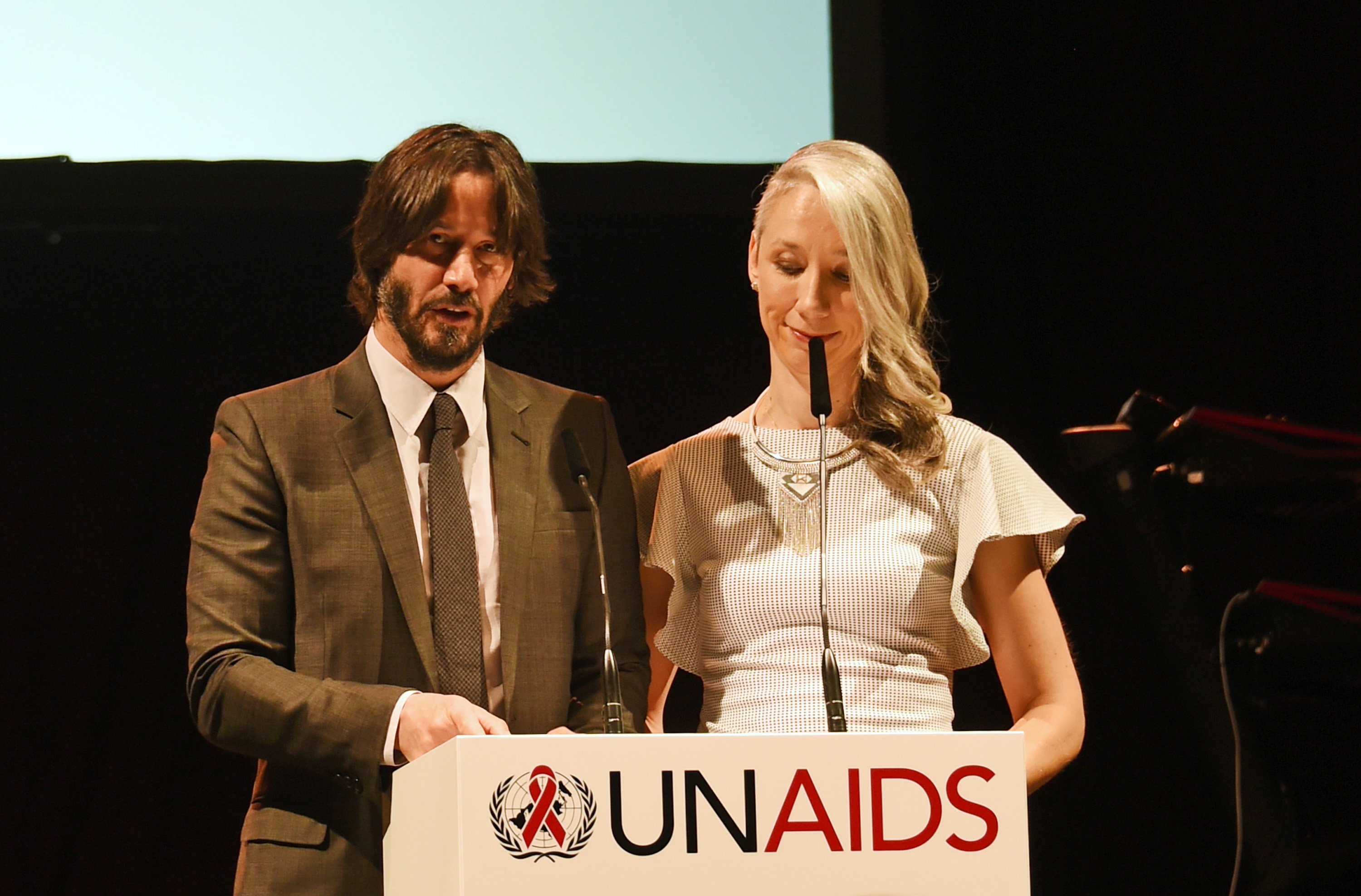 Keanu Reeves and Alexandra Grant speak at the UNAIDS Gala during Art Basel 2016 at Design Miami/ Basel on June 13, 2016 in Basel, Switzerland. | Image: Getty Images