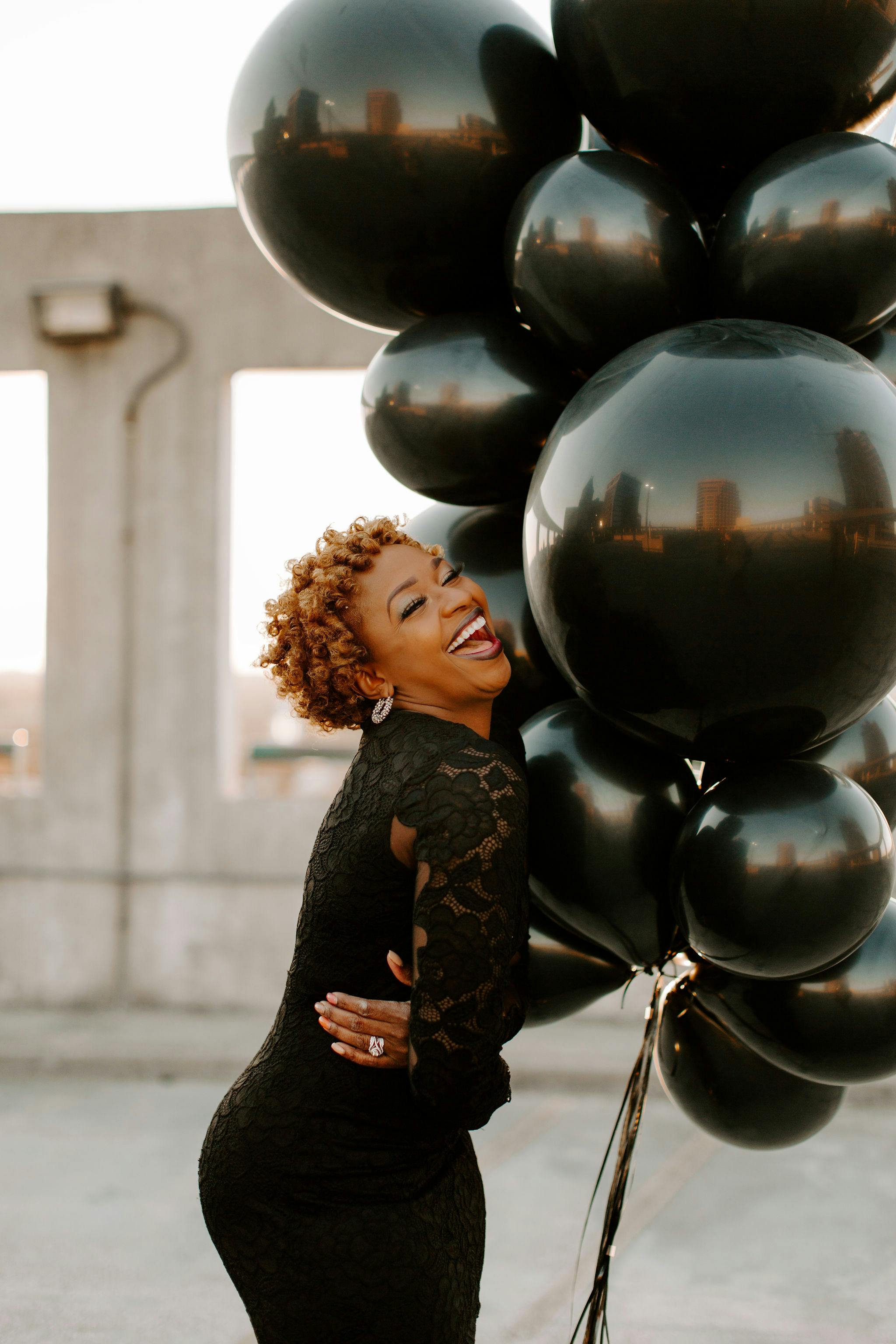 A woman laughing while holding balloons | Source: Pexels