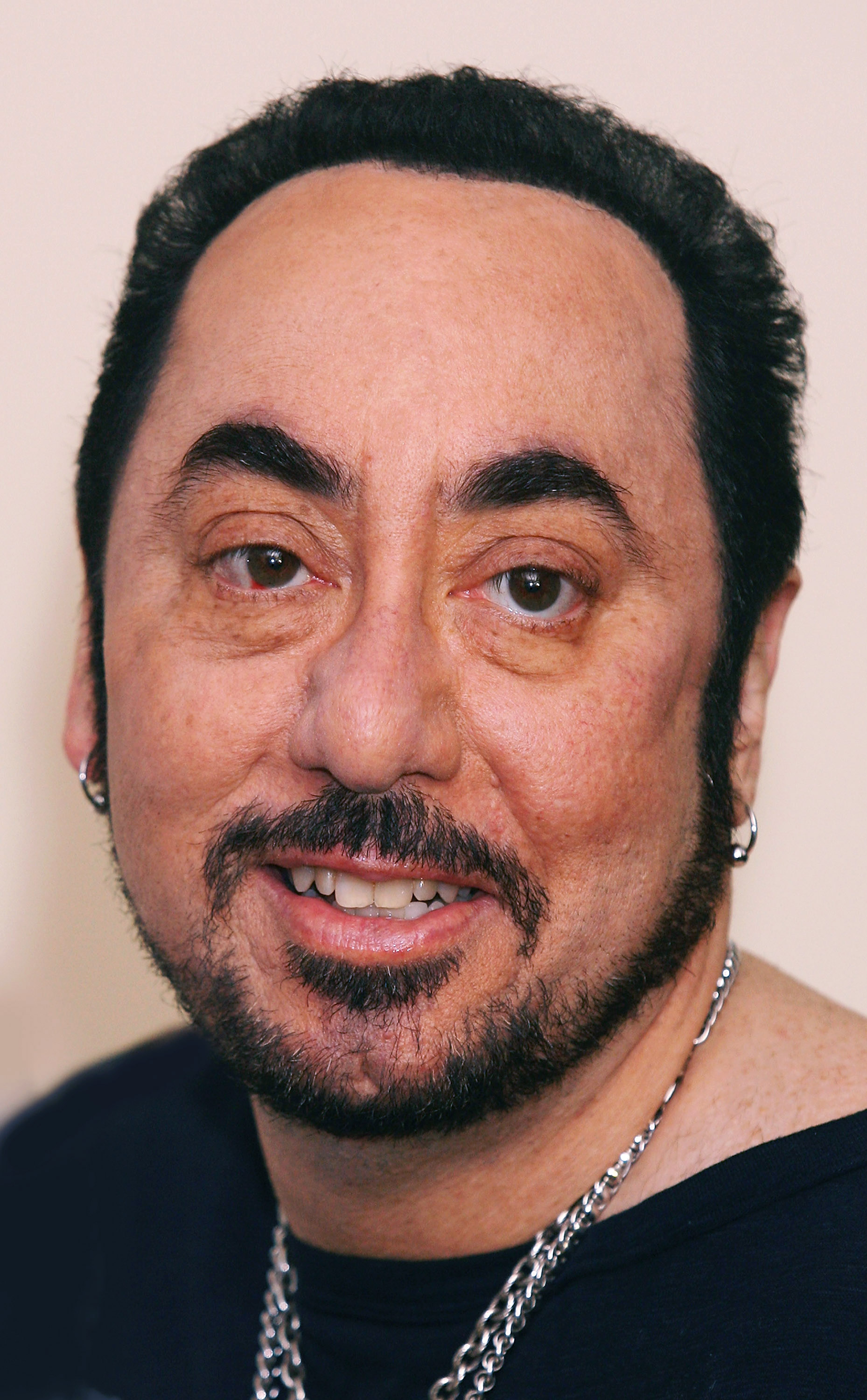 David Gest posed for a close-up at London's Grosvenor House Hotel on May 15, 2007, as he took on a new role as an ambassador for Caudwell Children's Charity. Wearing a neatly shaped beard, silver earrings, and layered chains, the music producer was photographed five years after his high-profile marriage to Liza Minnelli and during a period when British television had brought him renewed public attention.
