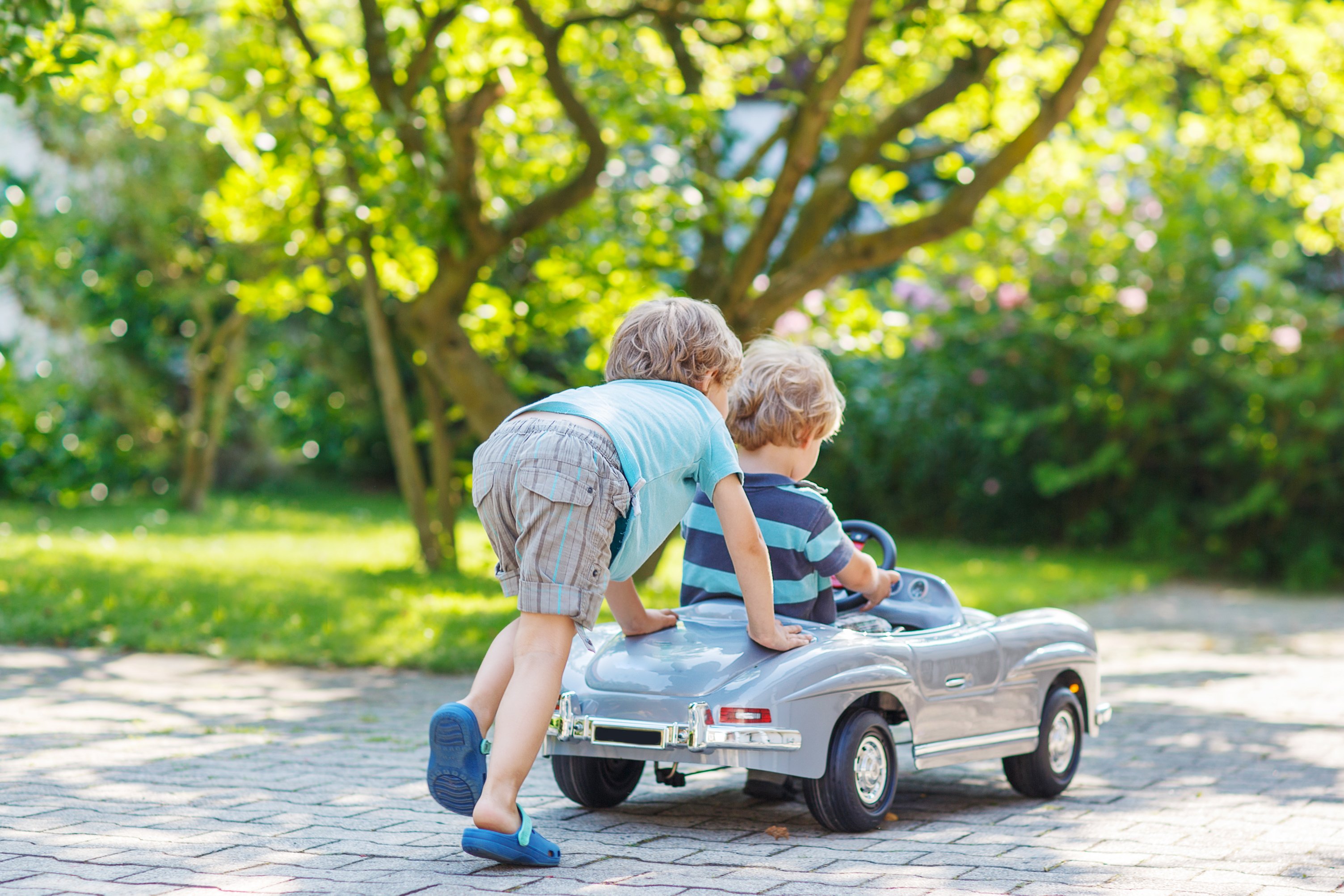 Two children playing with a toy car in a garden | Source: Shutterstock