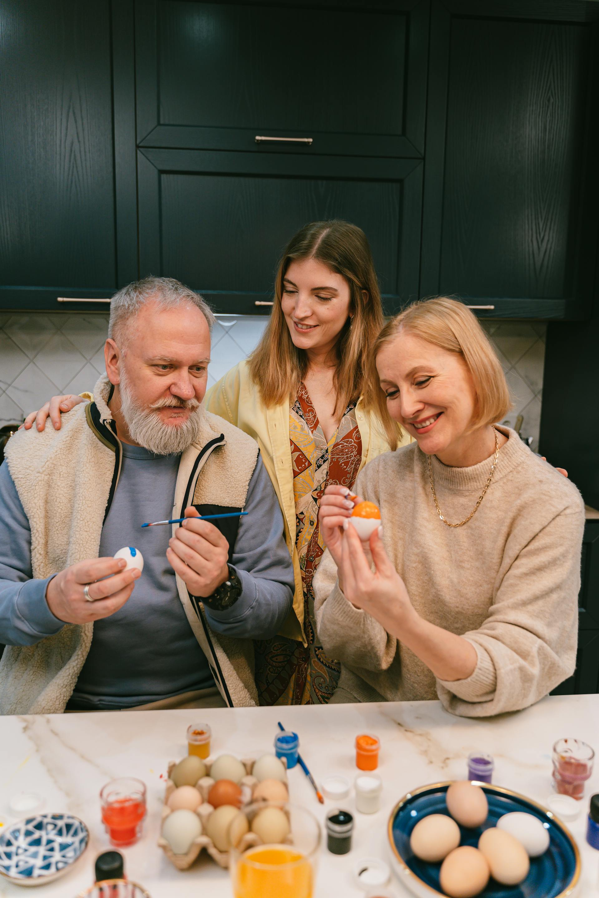 A woman watching her senior parents paint Easter eggs in the kitchen | Source: Pexels