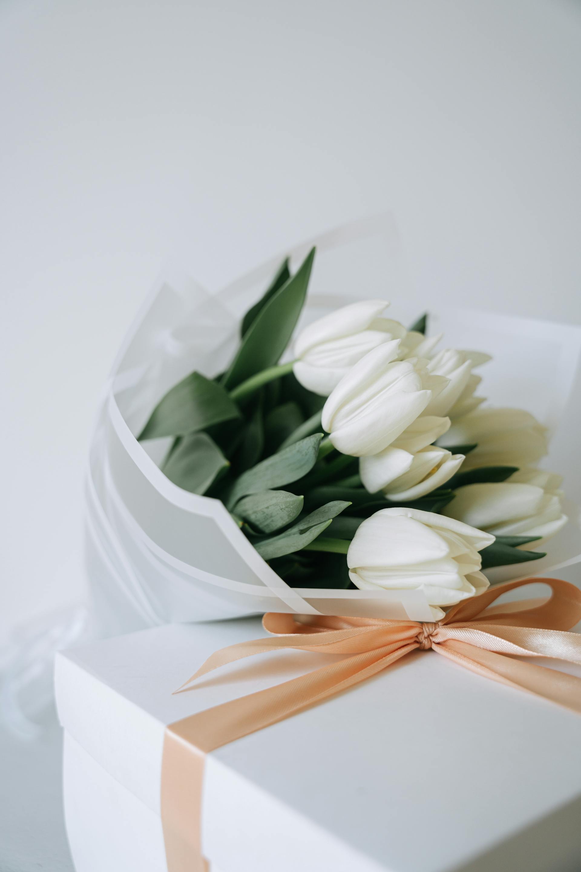 A bouquet of white tulips and a giftbox | Source: Pexels