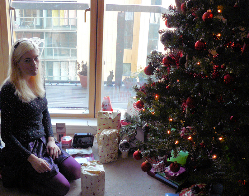 A sad woman sitting beside a Christmas tree | Source: Flickr