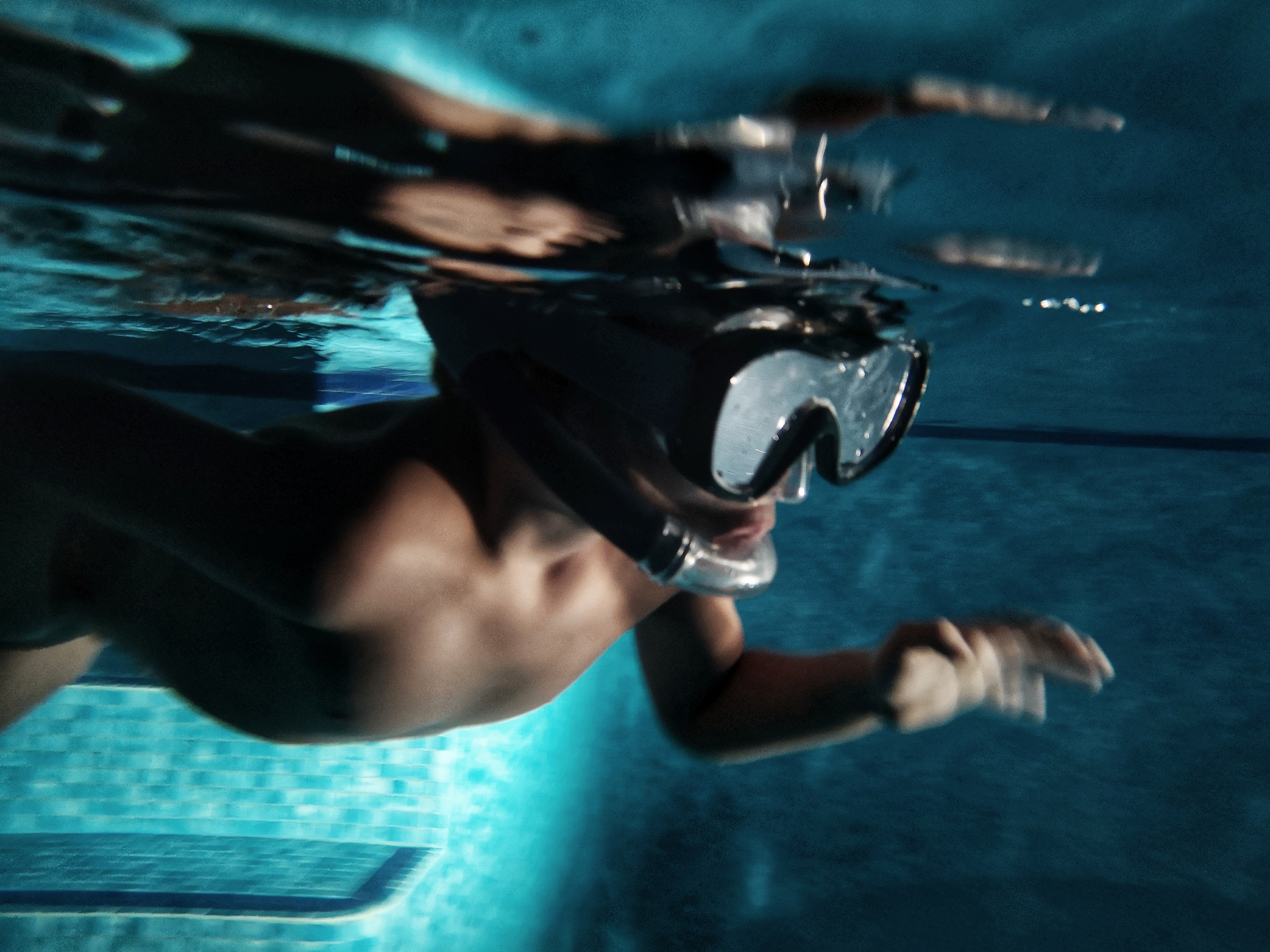 A diver with goggles on swims under the water | Photo: Unsplash/Alan Angelats
