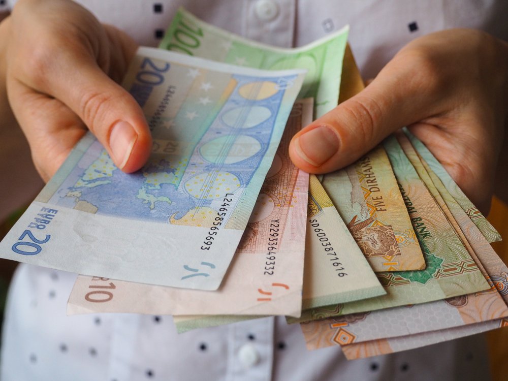 Manos que sostienen los euros en billetes. | Fuente: Shutterstock