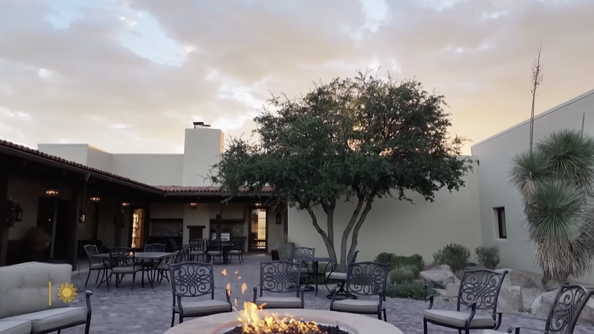A glowing fire pit anchors the courtyard of a Southwestern-style retreat nestled within the remote wilderness of Turner’s ranchland. | Source: YouTube/CBS Sunday Morning