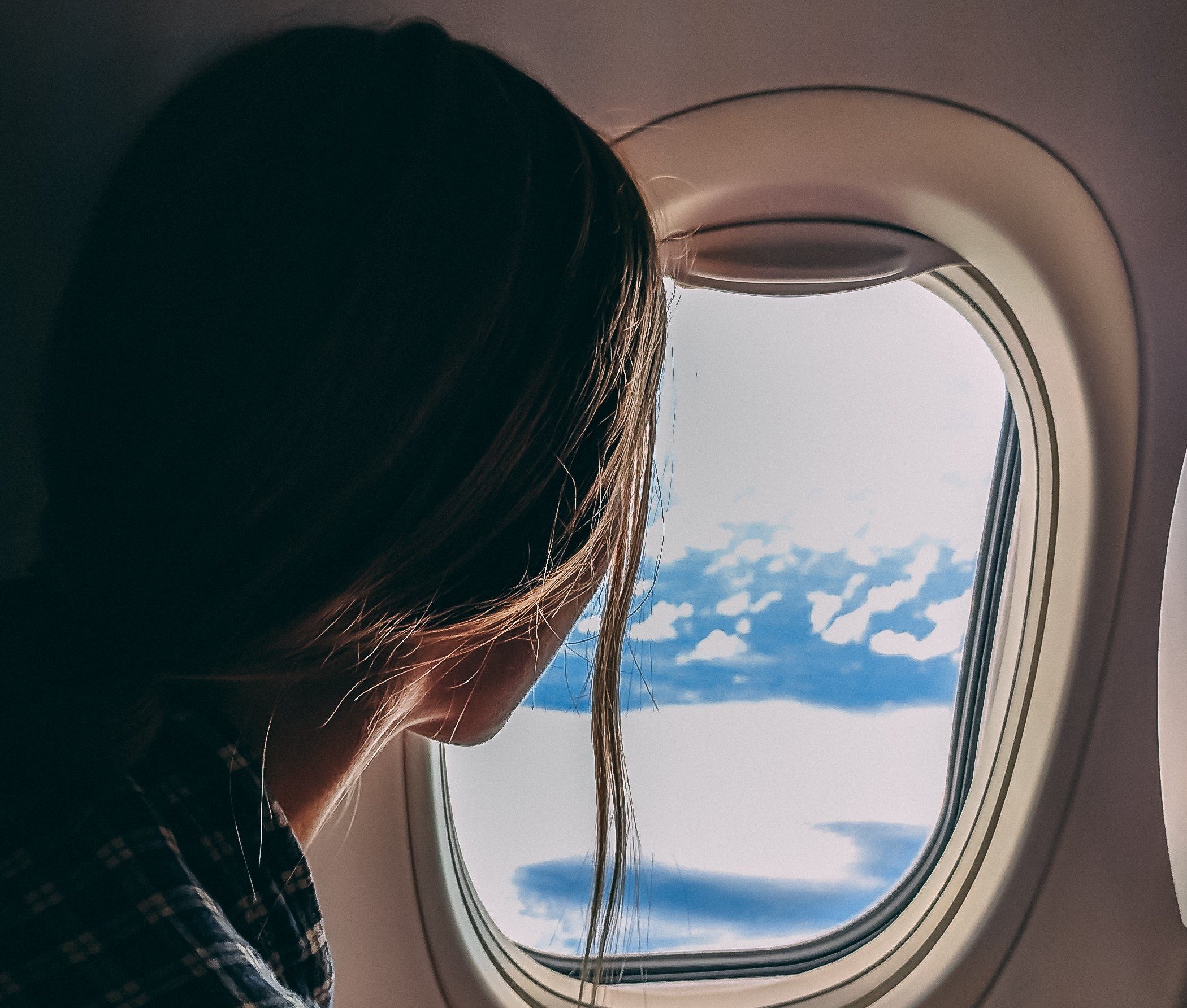 Una mujer mira por la ventanilla de un avión. | Foto: Pexels