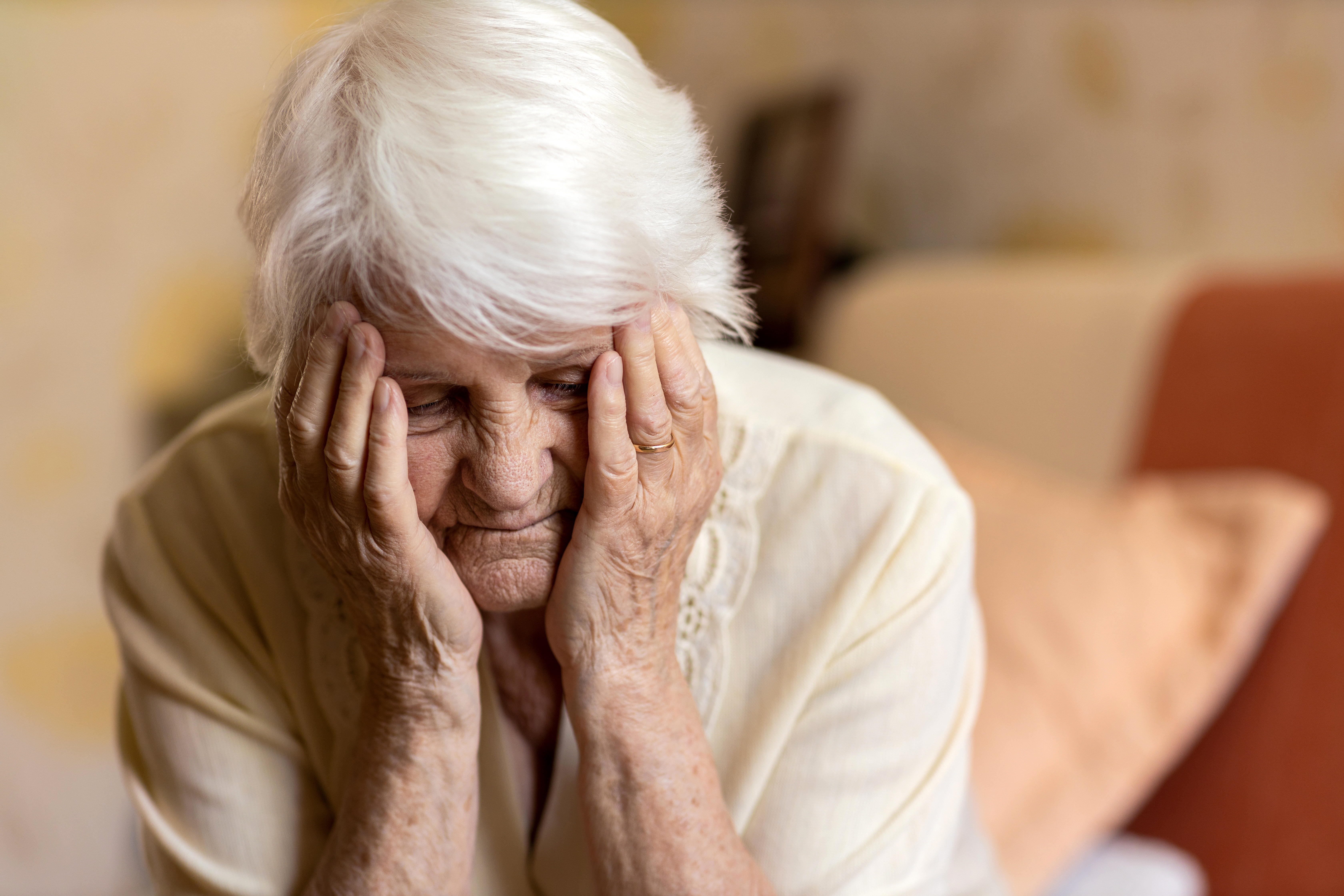 An older woman holding her head in her hands in despair | Source: Shutterstock