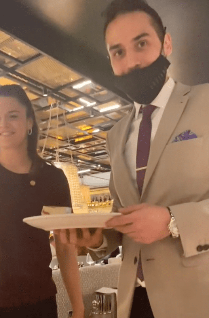 Two of the restaurant staff members present a blind woman a plate with a birthday message written in braille | Photo: TikTok/natbysight