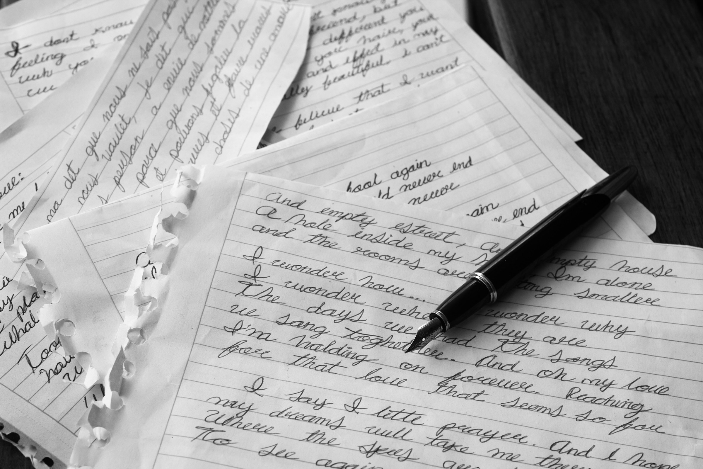 A pen lying on pieces of white paper with something written on them | Source: Unsplash