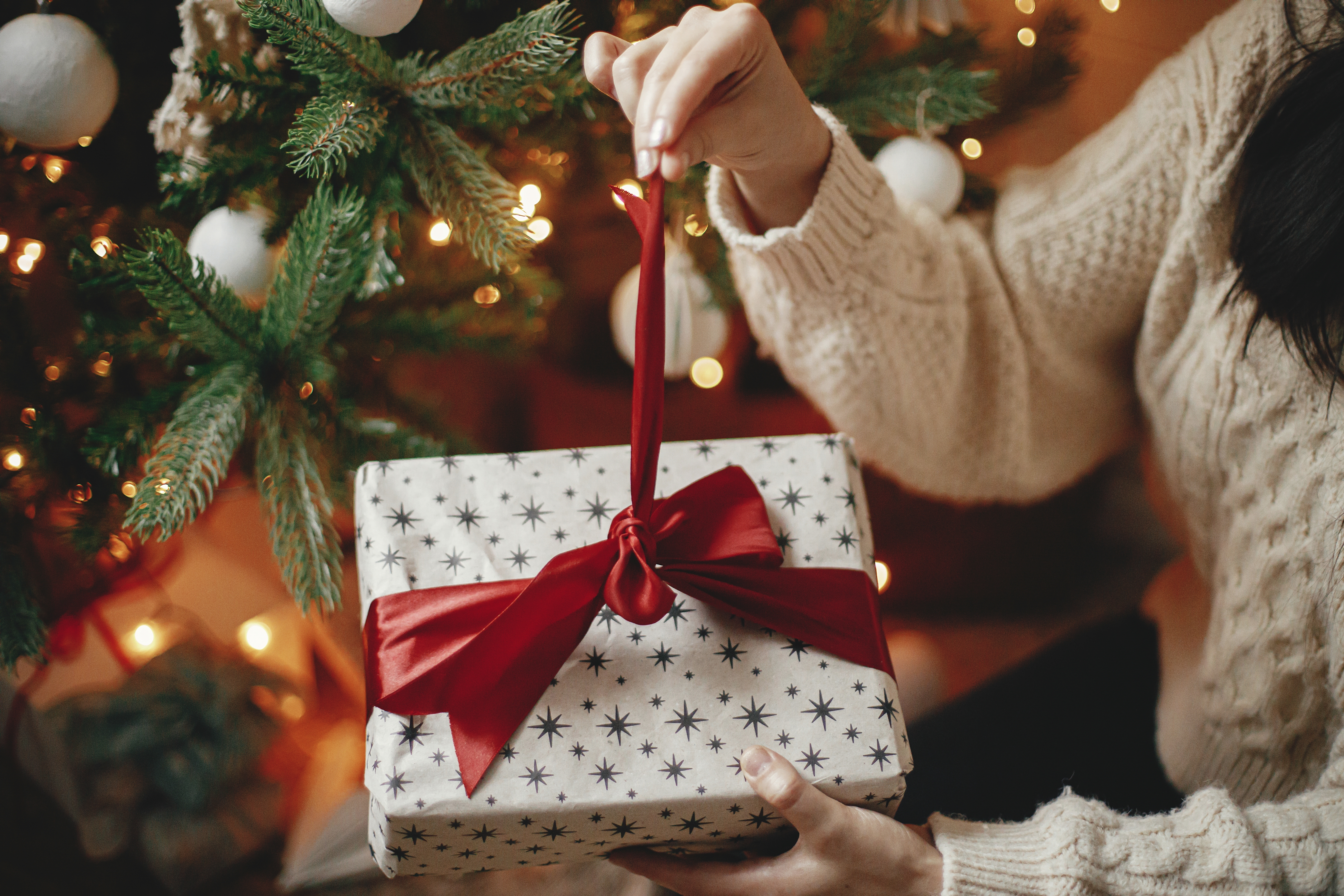 Hands in a cozy sweater opening a Christmas gift | Source: Shutterstock