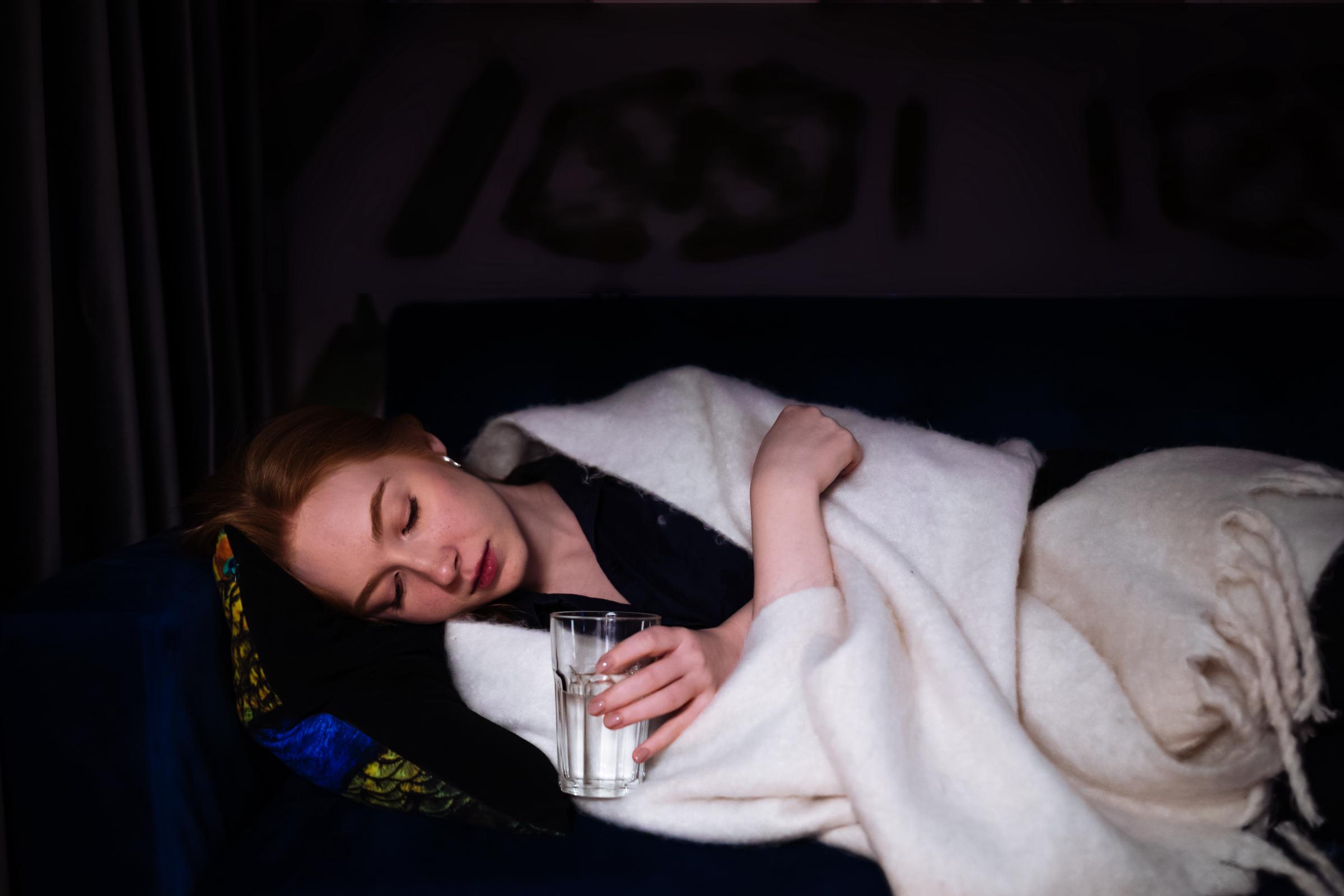 A sick woman resting on a sofa with a blanket. | Source: Getty Images