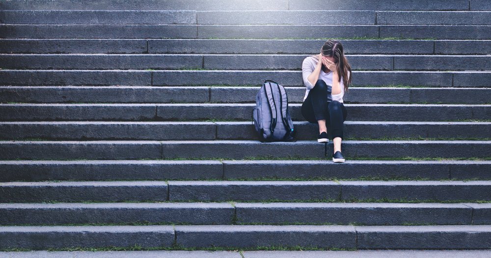 Adolescente sentada sola en unas escaleras. | Foto: Shutterstock.