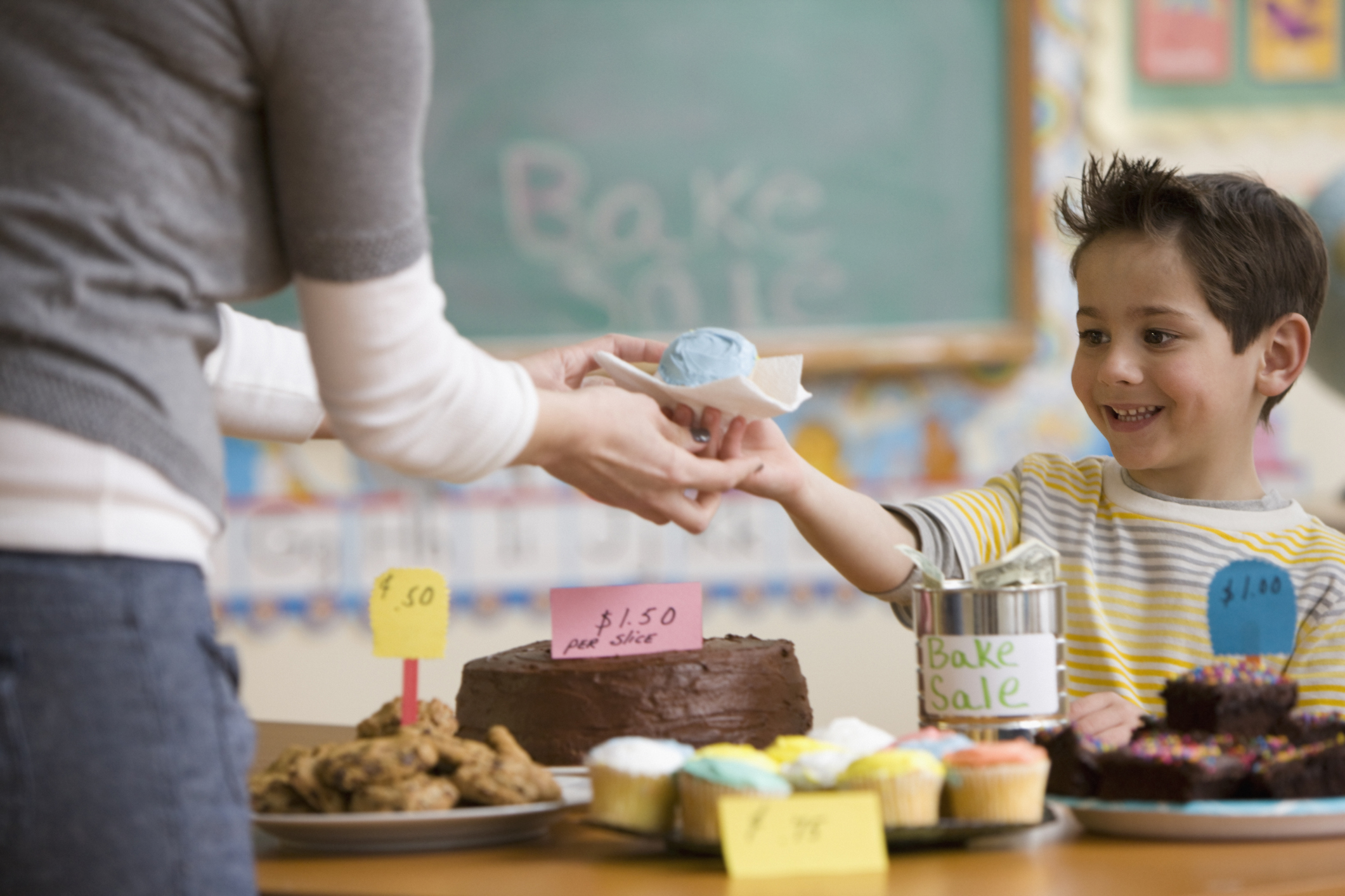 A little boy pictured handing over a cupcake during a school bake sale | Source: Getty Images