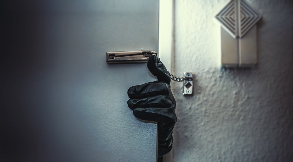 Ein maskierter Einbrecher bricht in eine Wohnung ein. I Quelle: Shutterstock