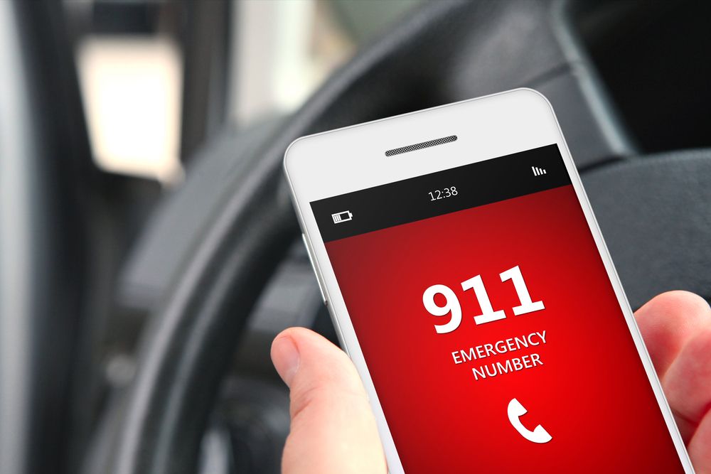 A man holding a cellphone to call 911 while inside a car. | Source: Shutterstock