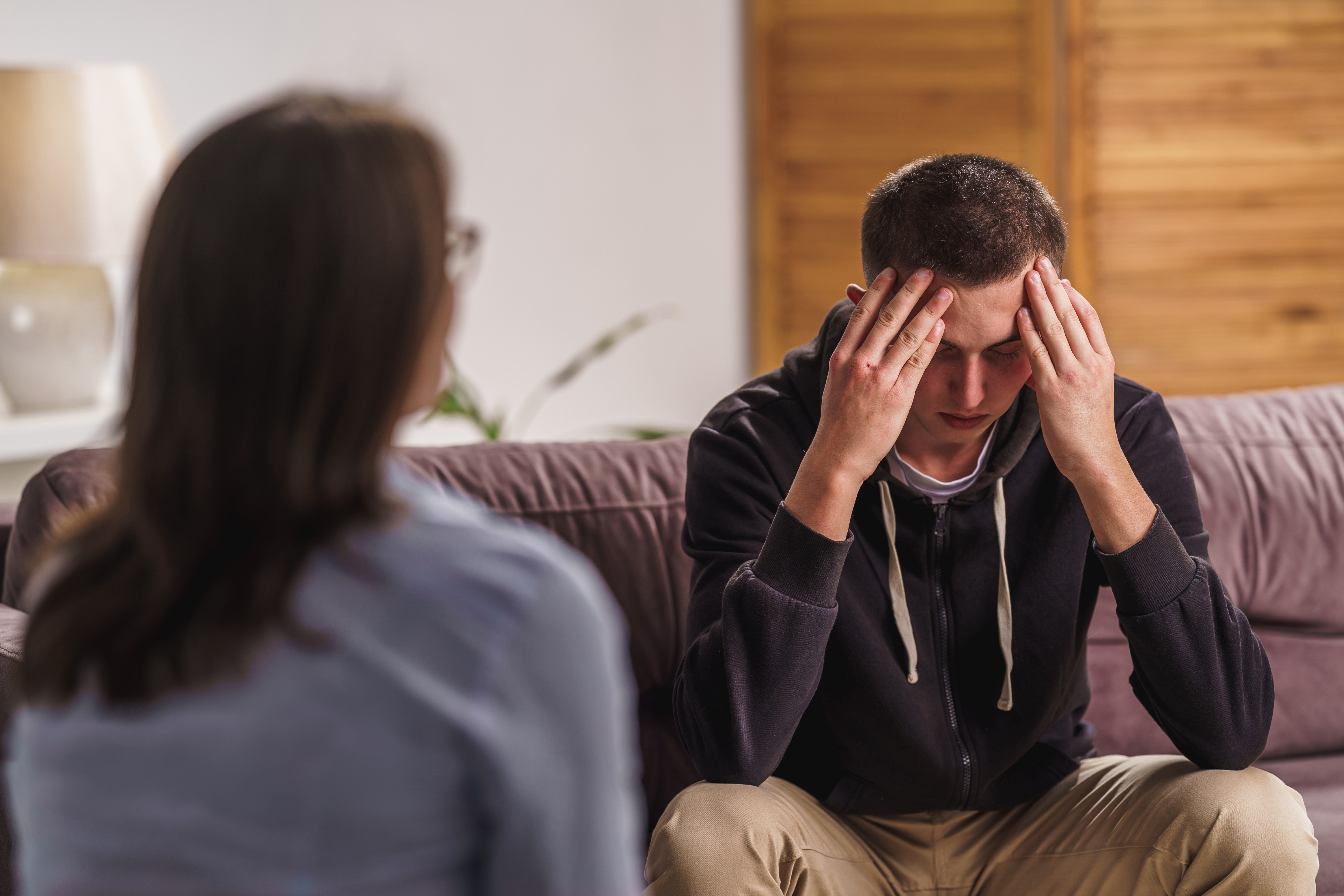 A teenage boy looking sad while speaking to a woman | Source: Shutterstock