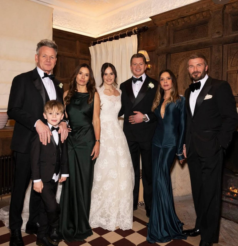 Gathered for a family portrait beside a glowing fireplace, Holly Ramsay and Adam Peaty stood alongside Gordon Ramsay, Tana Ramsay, and their son, joined by Victoria and David Beckham. Still dressed in her lace Elie Saab wedding gown, Holly was captured before her outfit change, marking a moment of togetherness during the formal celebrations. | Source: Instagram/britishvogue
