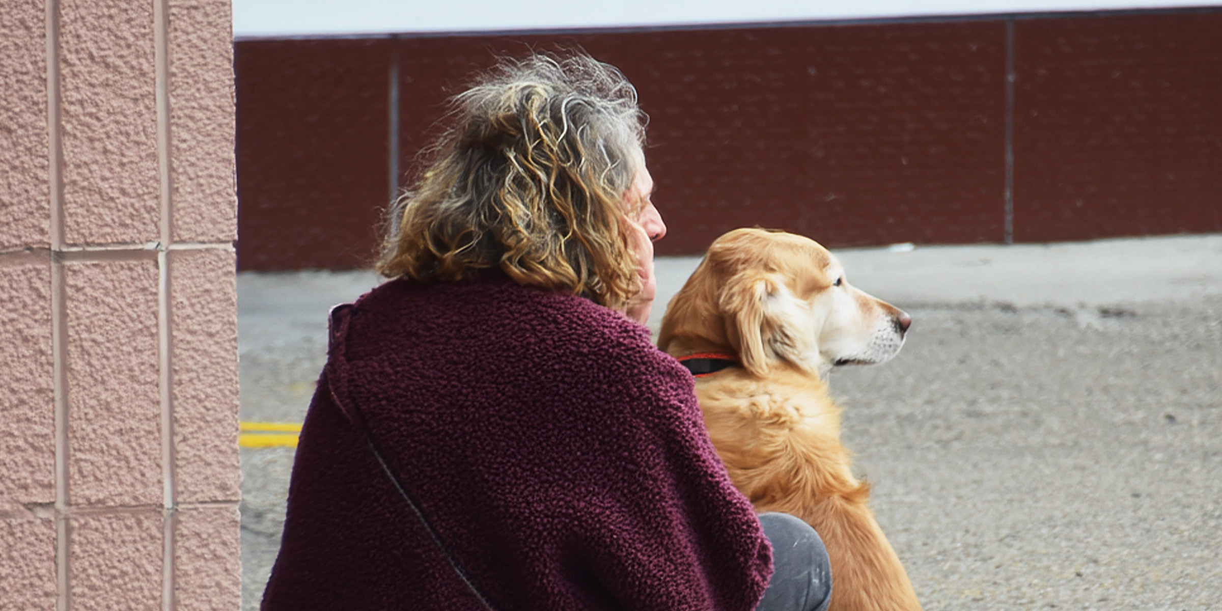A woman and her dog sitting on a sidewalk | Source: AmoMama