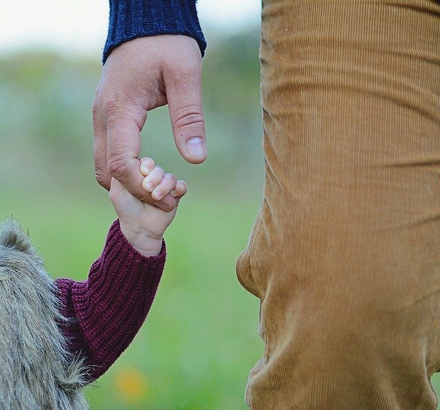 Man holds his daughter's hand while walking | Photo: Pixabay