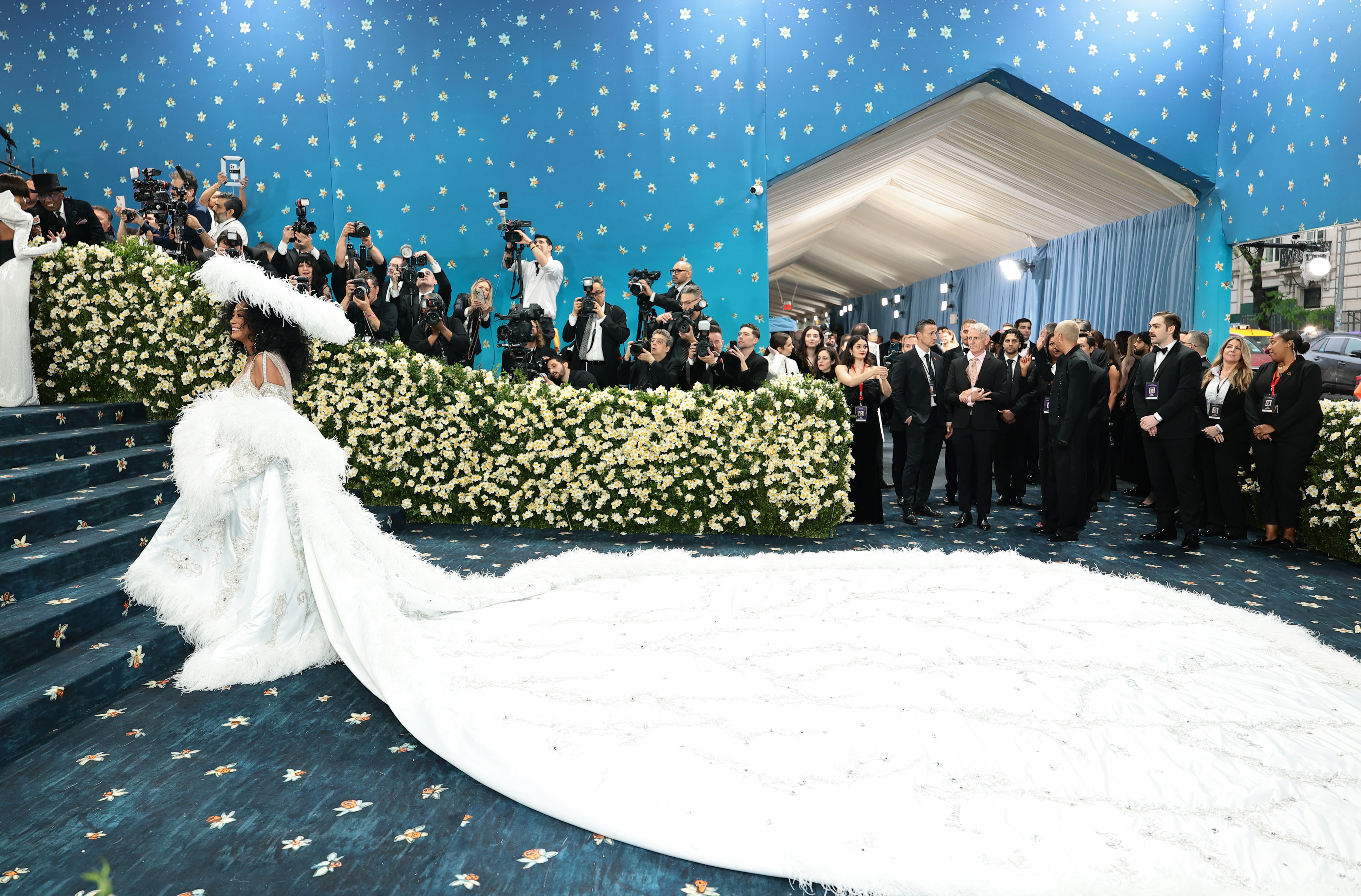 Ross stands in all her glory, her back to the Met Gala entrance as she takes in the moment. Photographers line the sides, capturing every angle, while onlookers behind her can’t help but pause, some mid-step, completely captivated by her presence and simply staring in awe.