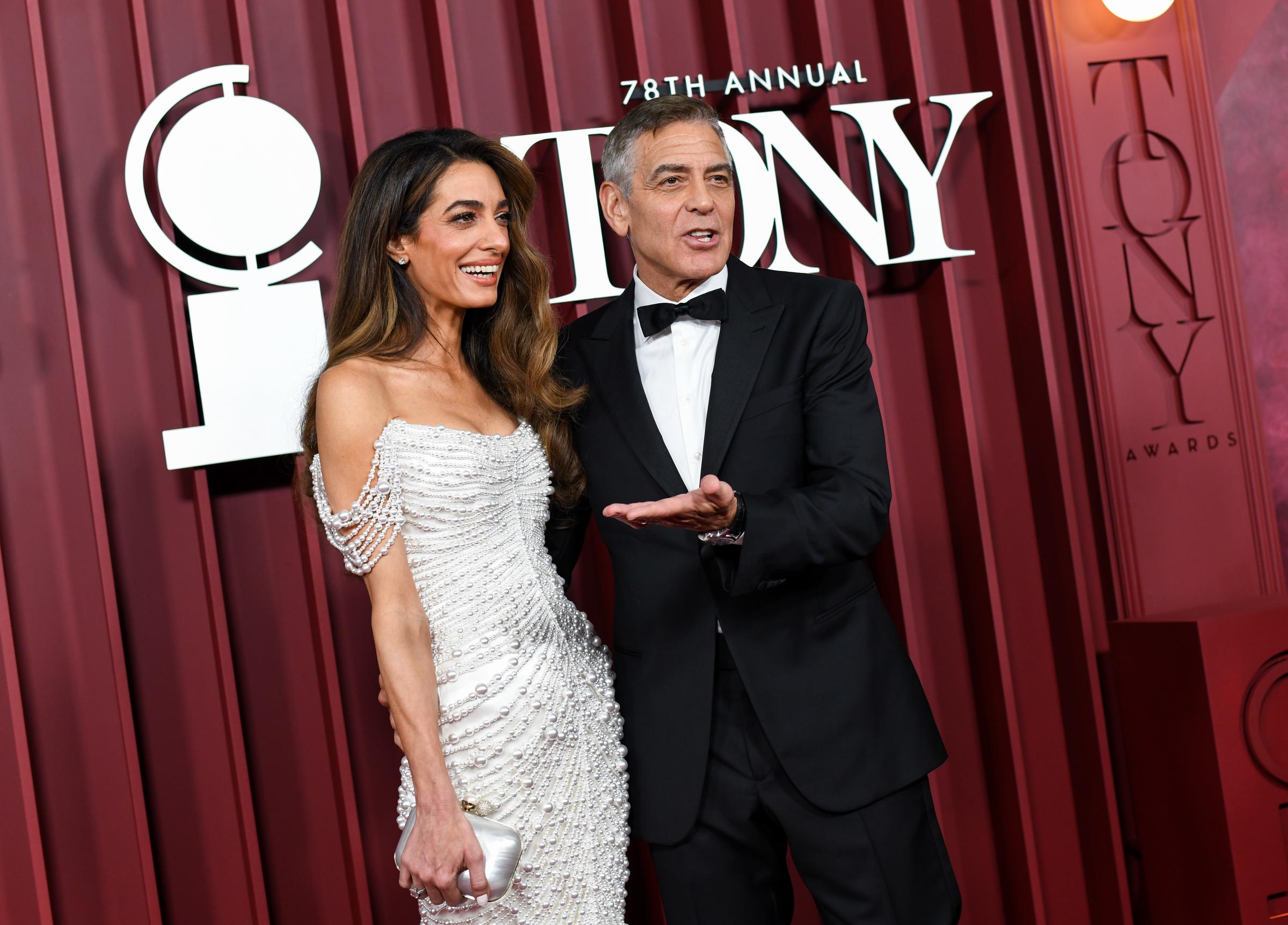 Amal and George Clooney share a lighthearted exchange as they arrive at the Tony Awards. George gestures mid-sentence while Amal laughs, adding a candid energy to the red carpet.