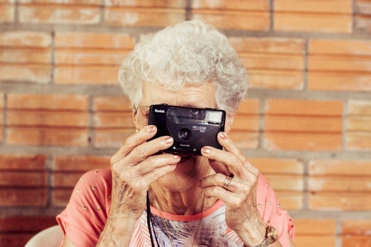 Une dame aux cheveux blancs tenant un appareil photo. | Source : Pixabay