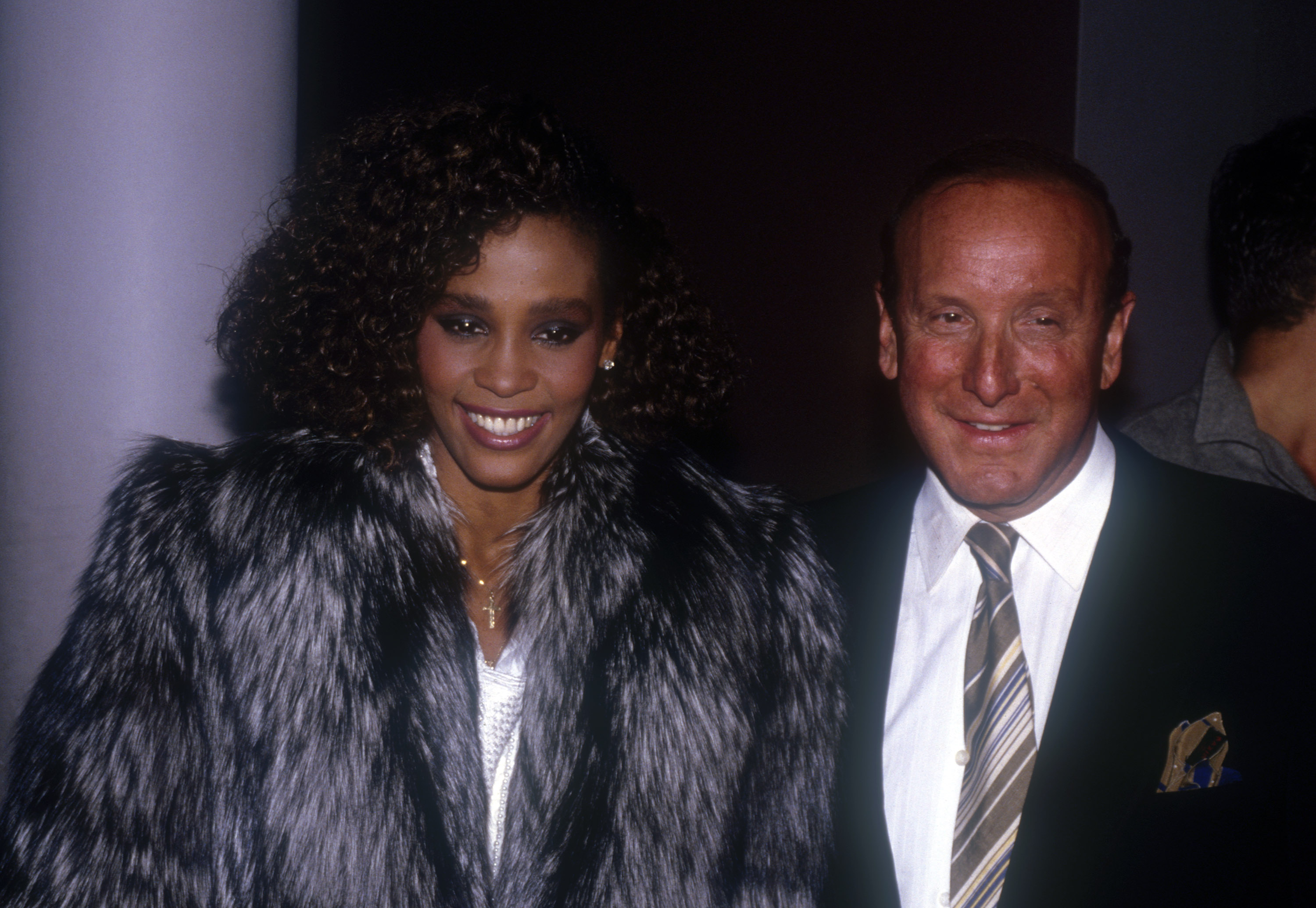 Some artists even had to defend him. On this occasion, he posed with Whitney Houston at an event to celebrate her debut album "Whitney Houston" receiving a multi-platinum sales award in 1985, in New York City, New York. | Source: Getty Images