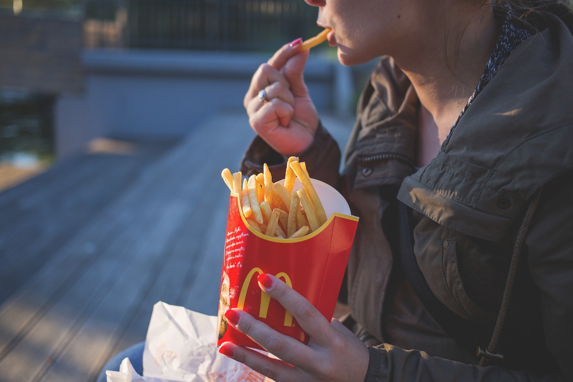 A woman eating a large box of McDonald's French fries | Photo: Pixabay/Pexels